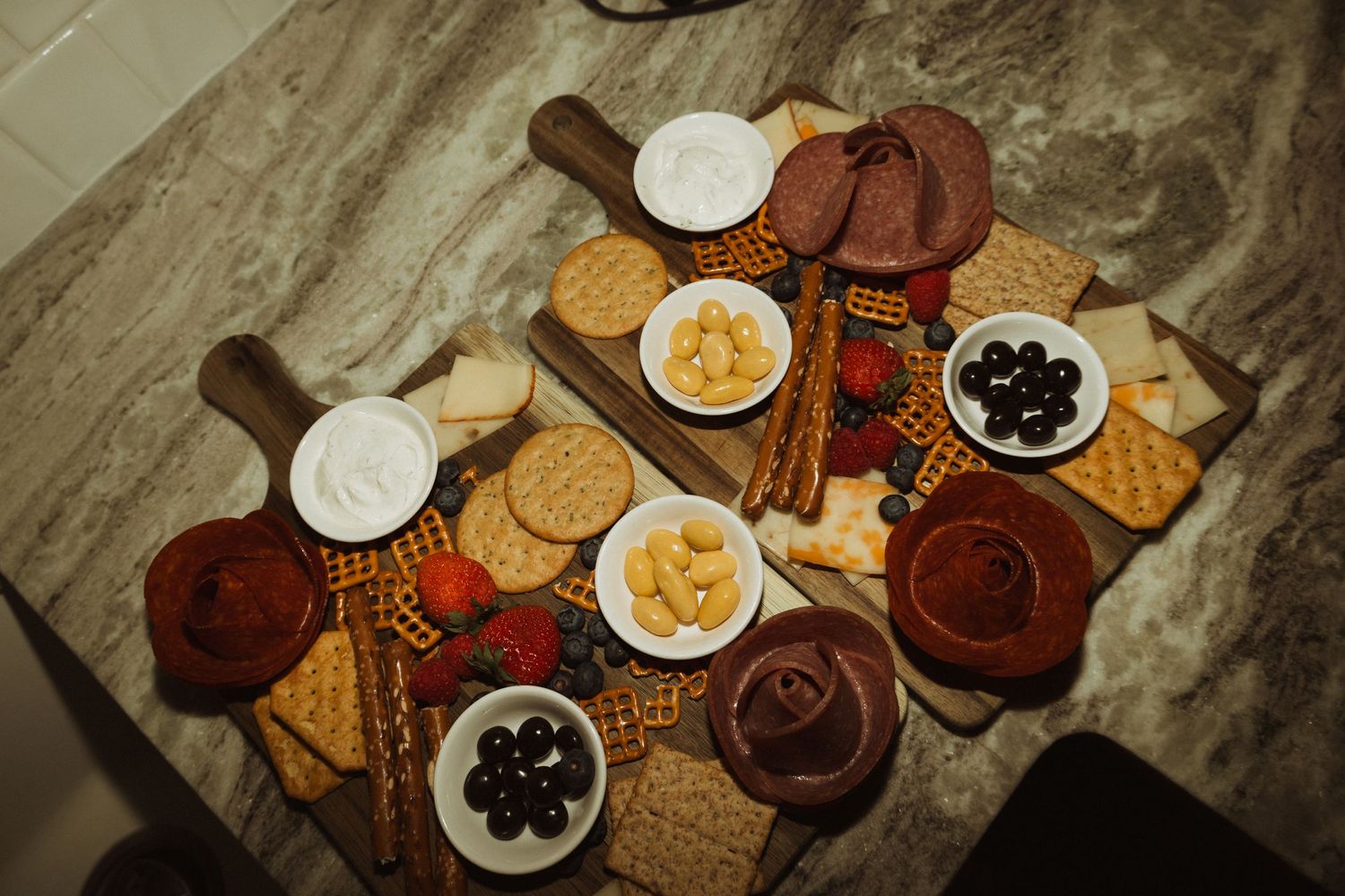 Charcuterie board spread with various cheeses, crackers, and accompaniments on marble surface.