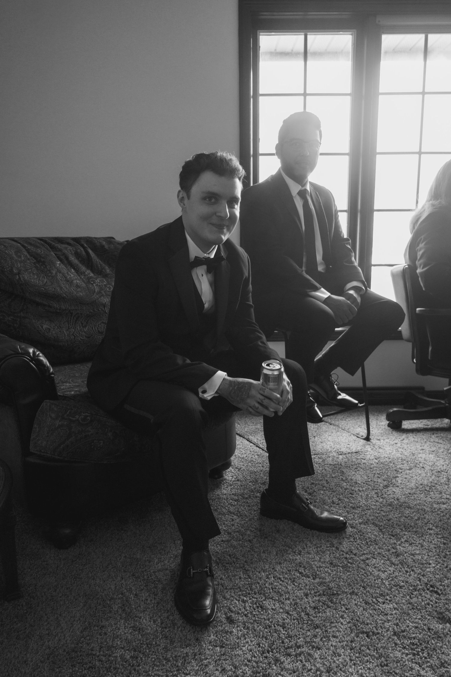 Black and white photo of groomsmen relaxing on couches before the ceremony.