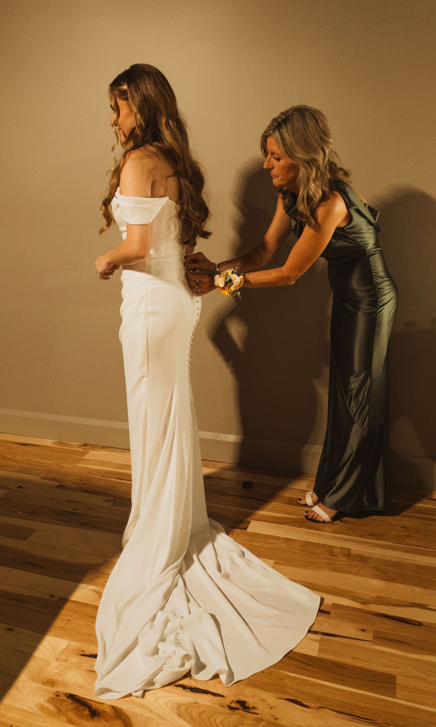 Series of photos showing the detailed adjustments of a white wedding dress on hardwood flooring.