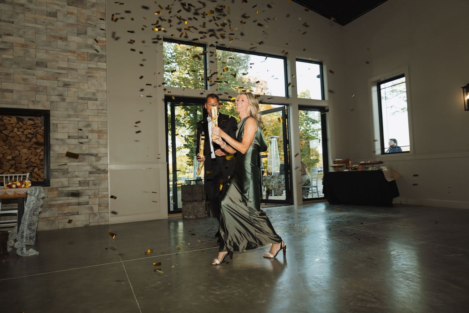 Couples dancing in an elegant venue with stone walls and large windows.