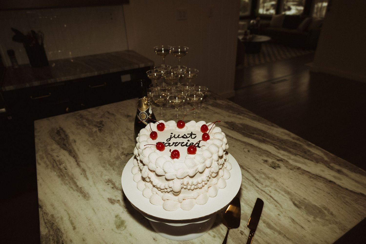 White wedding cake decorated with red berries and cream frosting on marble surface.