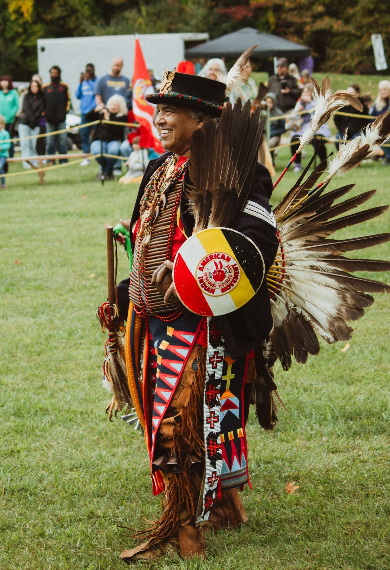 A Native American dancer in traditional regalia with feathers and beadwork performs at an outdoor festival.