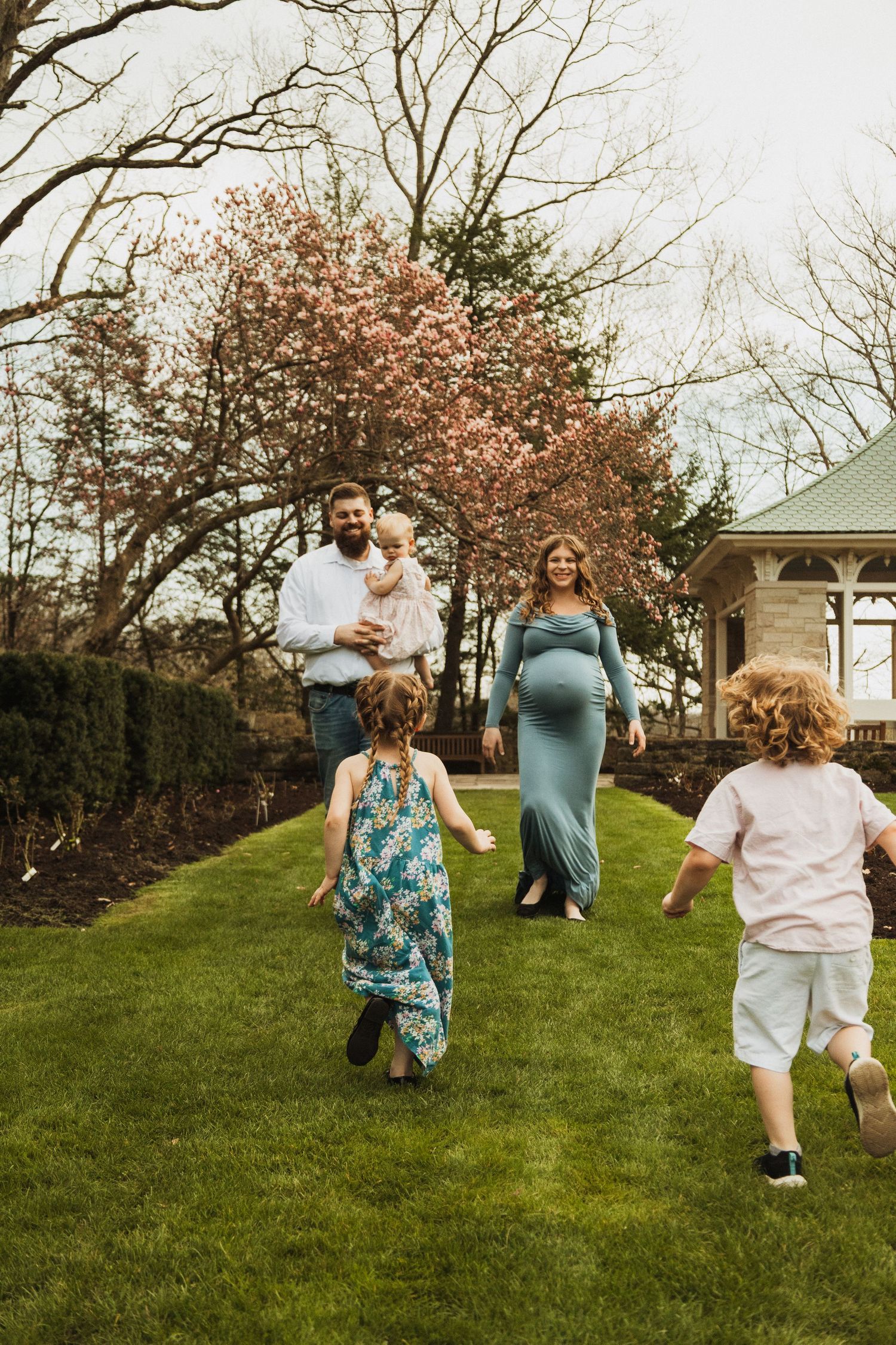 Family group enjoys springtime outdoors with blooming cherry trees in a garden setting.