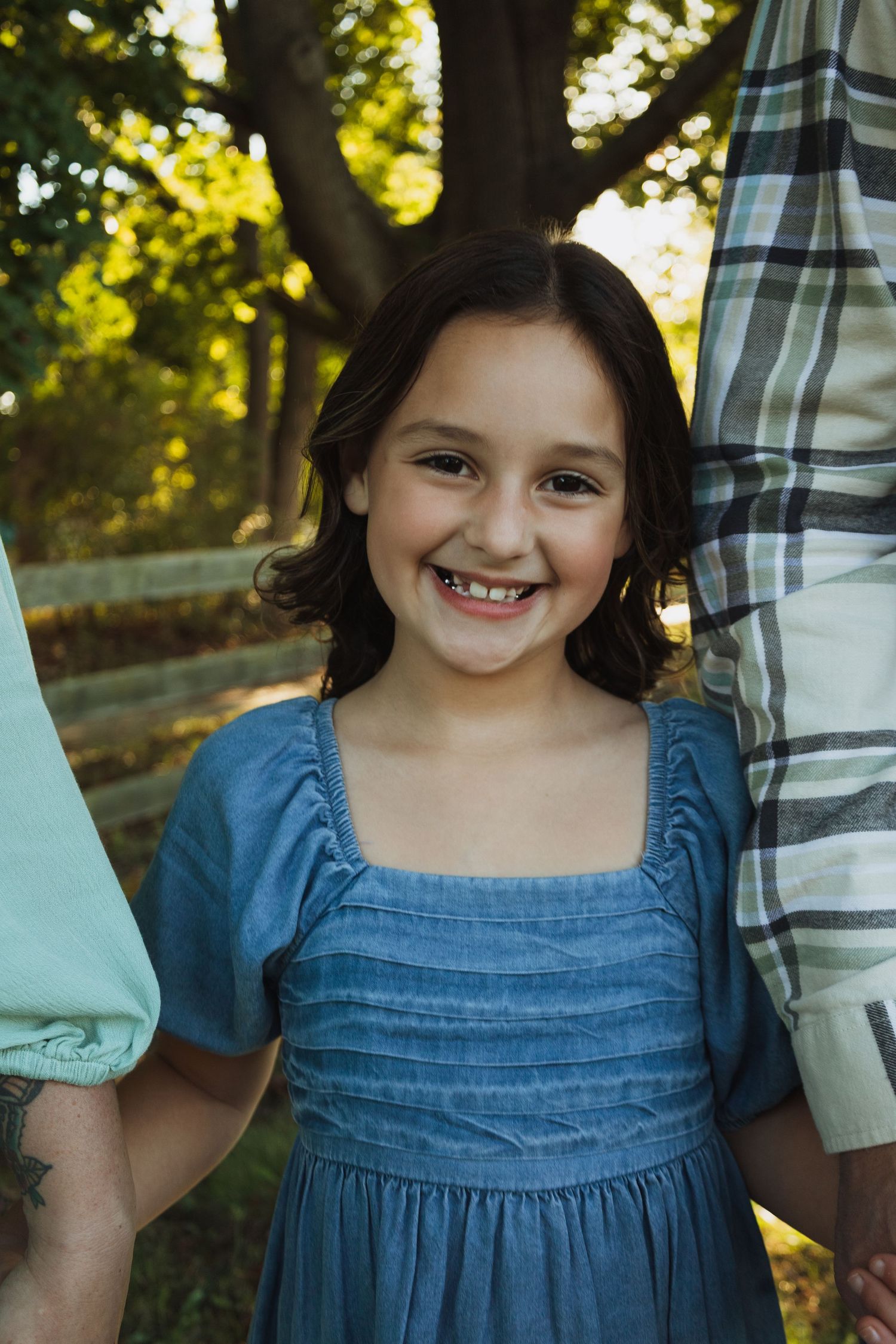 A sequence of four candid photos showing a child in a blue dress outdoors with sunlit trees in the background.