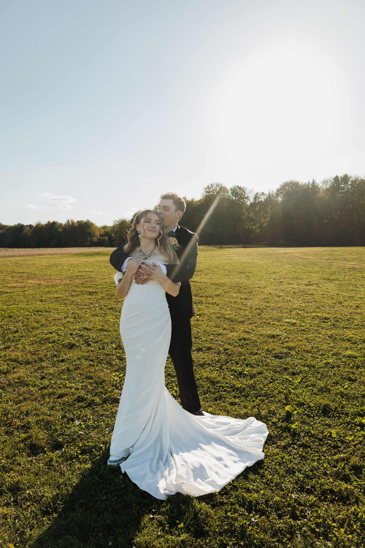 Newlyweds dancing and twirling in a sunlit meadow with the bride's dress catching the light.