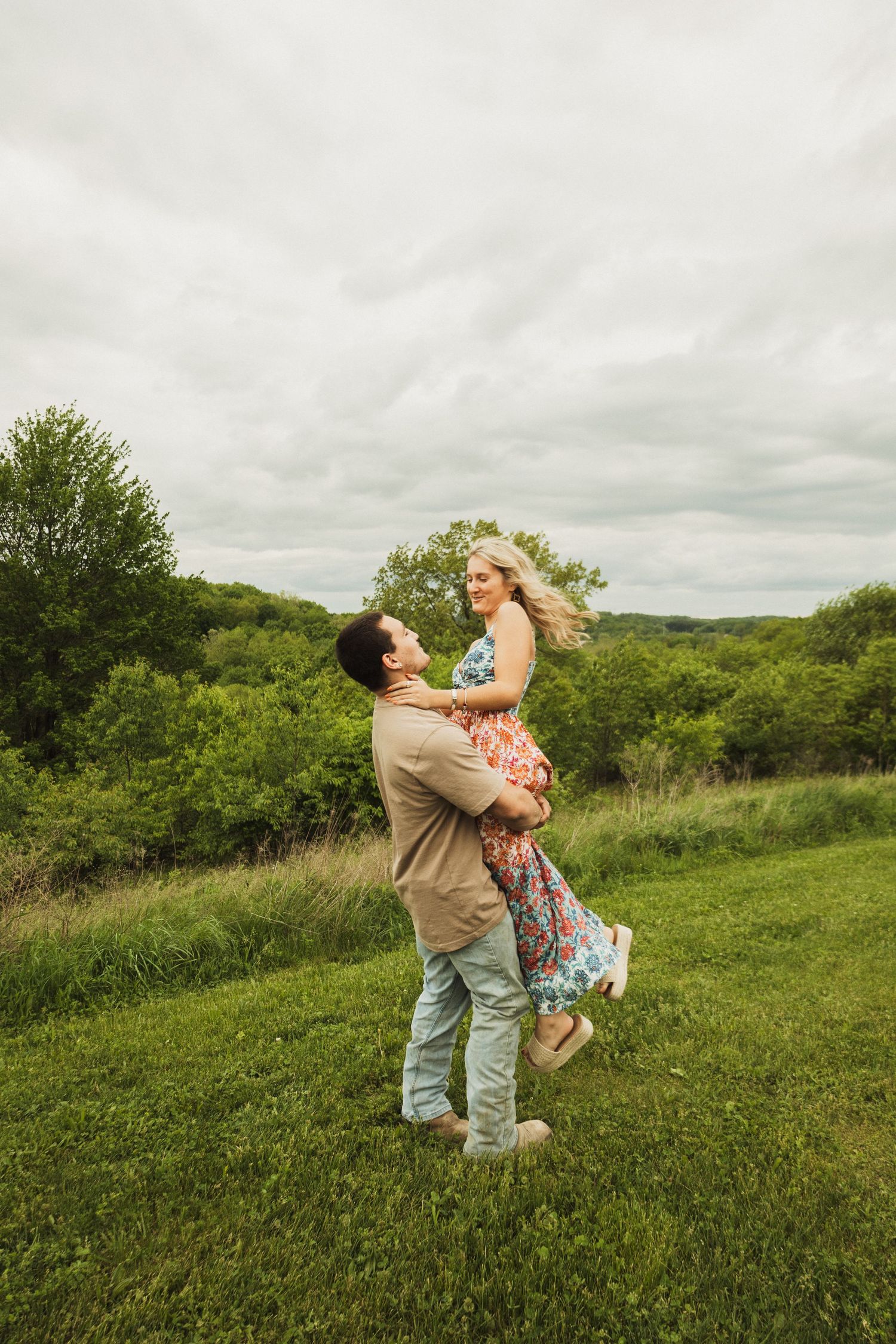 A romantic moment captured as a couple dances and spins together in a scenic meadow.