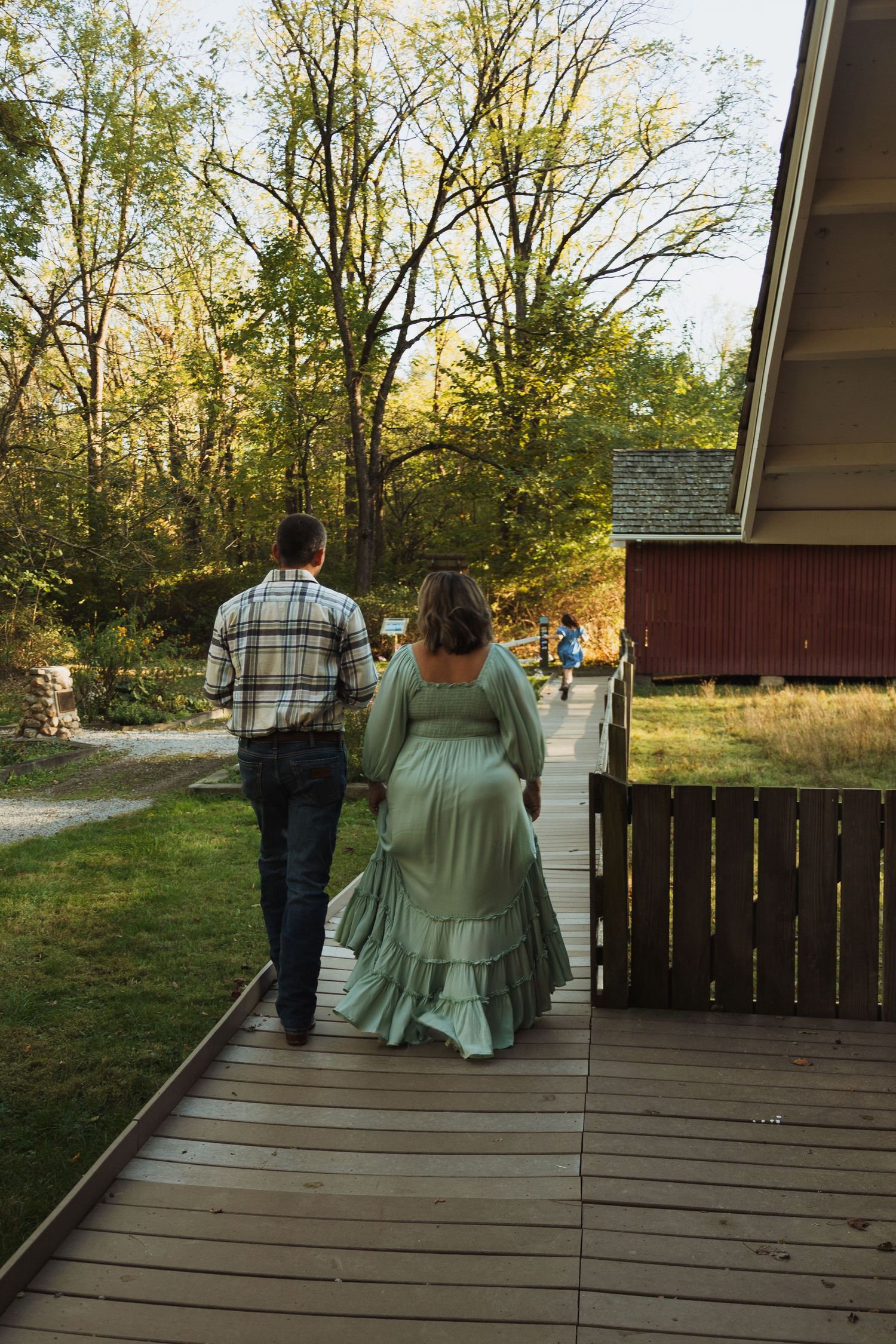 A couple sits together on a wooden deck surrounded by autumn trees at sunset.
