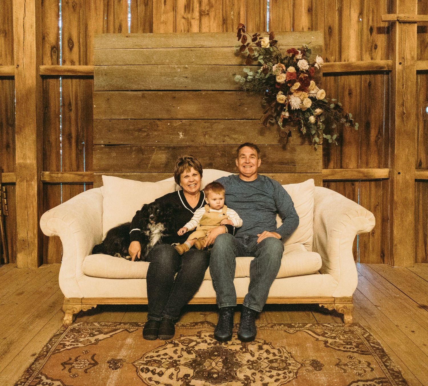 Small group seated on white couch in rustic wooden interior setting.