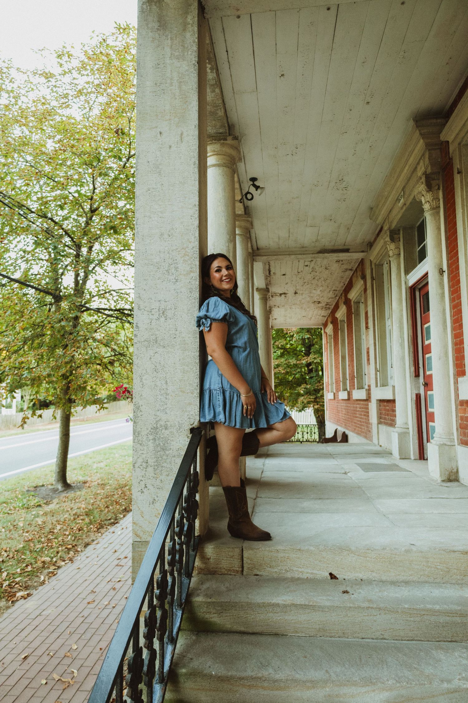 Person in blue dress sitting along covered walkway with columns.
