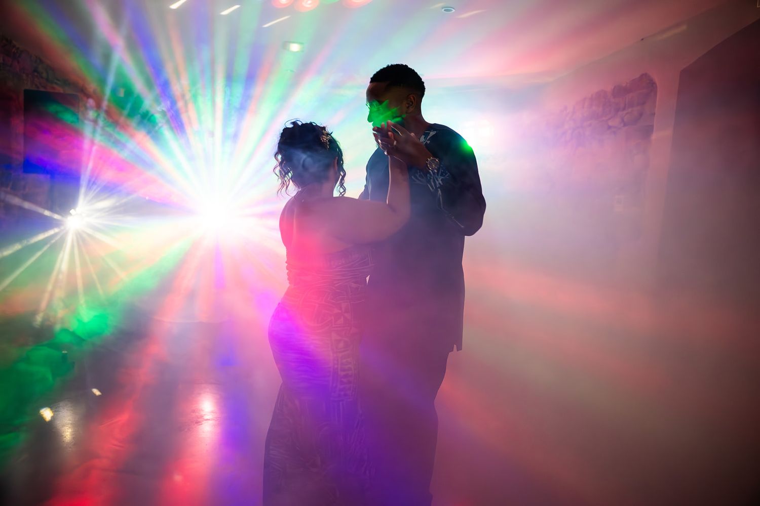 Silhouettes dance under colorful disco lights and beams in a nightclub atmosphere.