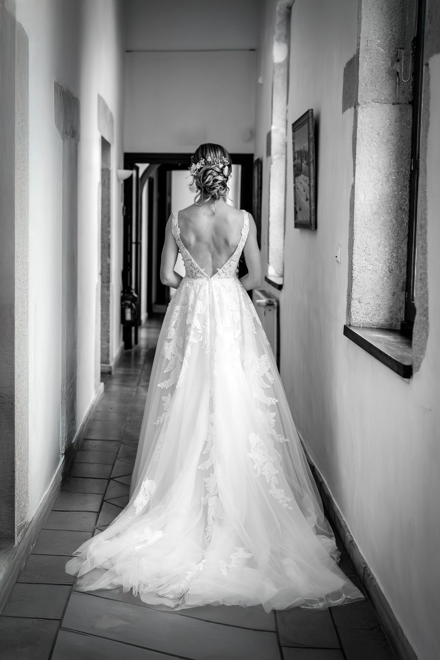Wedding dress with flowing train photographed in elegant hallway from multiple angles.