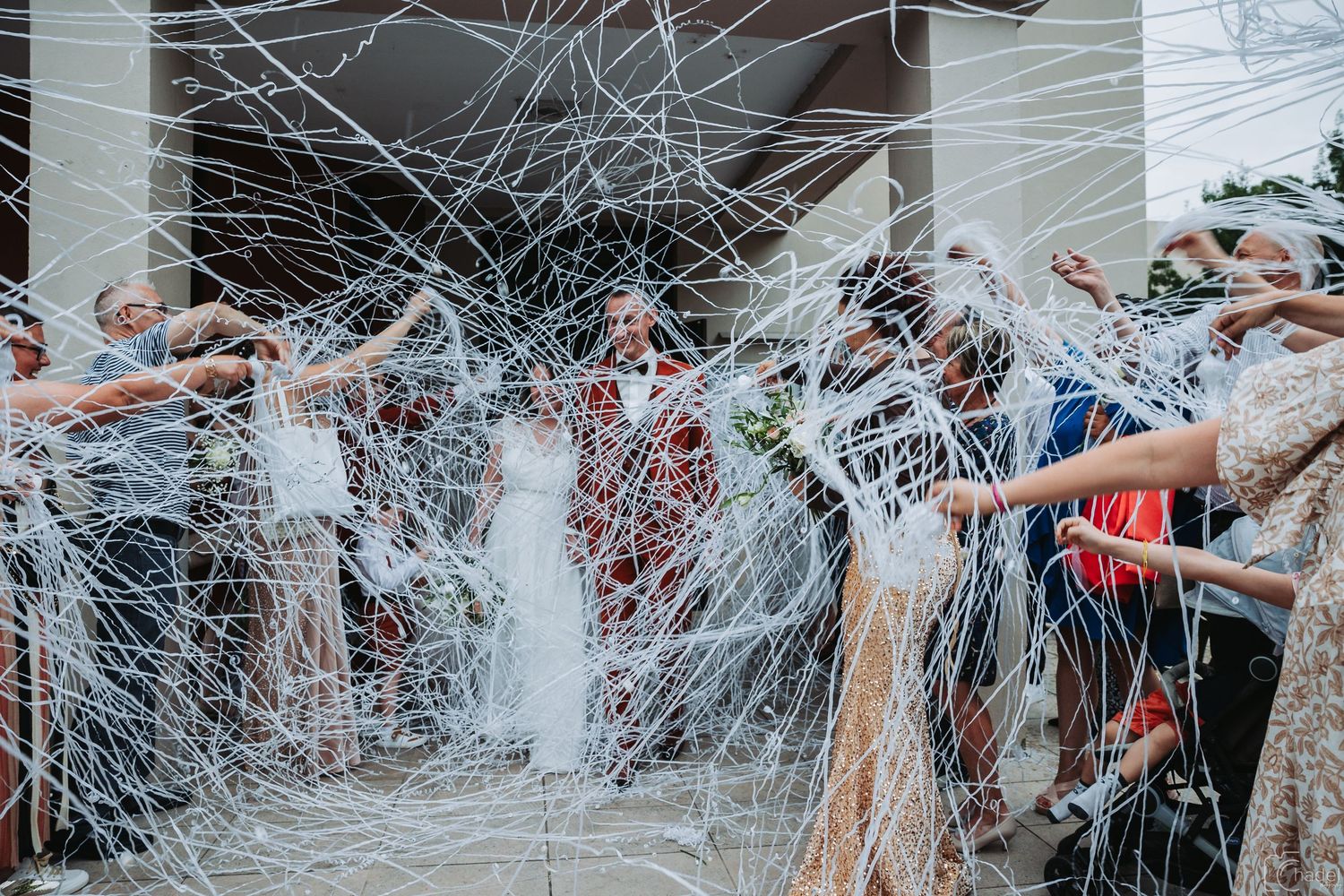 Wedding guests joyfully throw white streamers in celebration at an outdoor reception venue.
