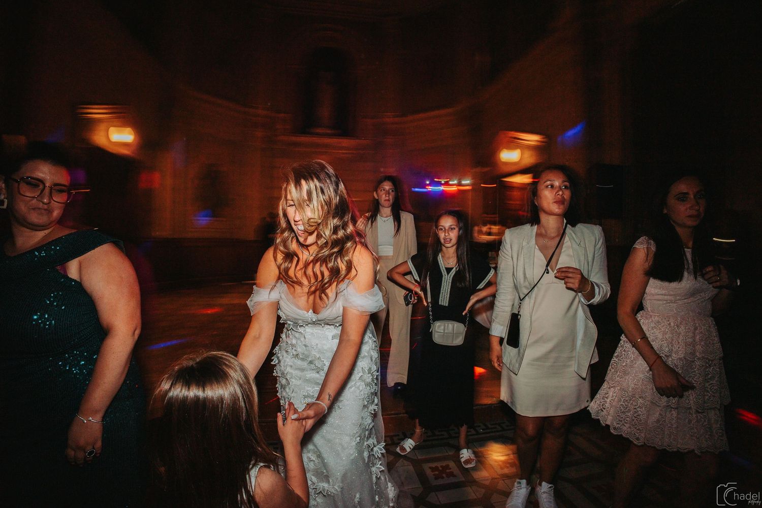 People dancing and socializing at a dimly lit nightclub or party venue with atmospheric lighting.