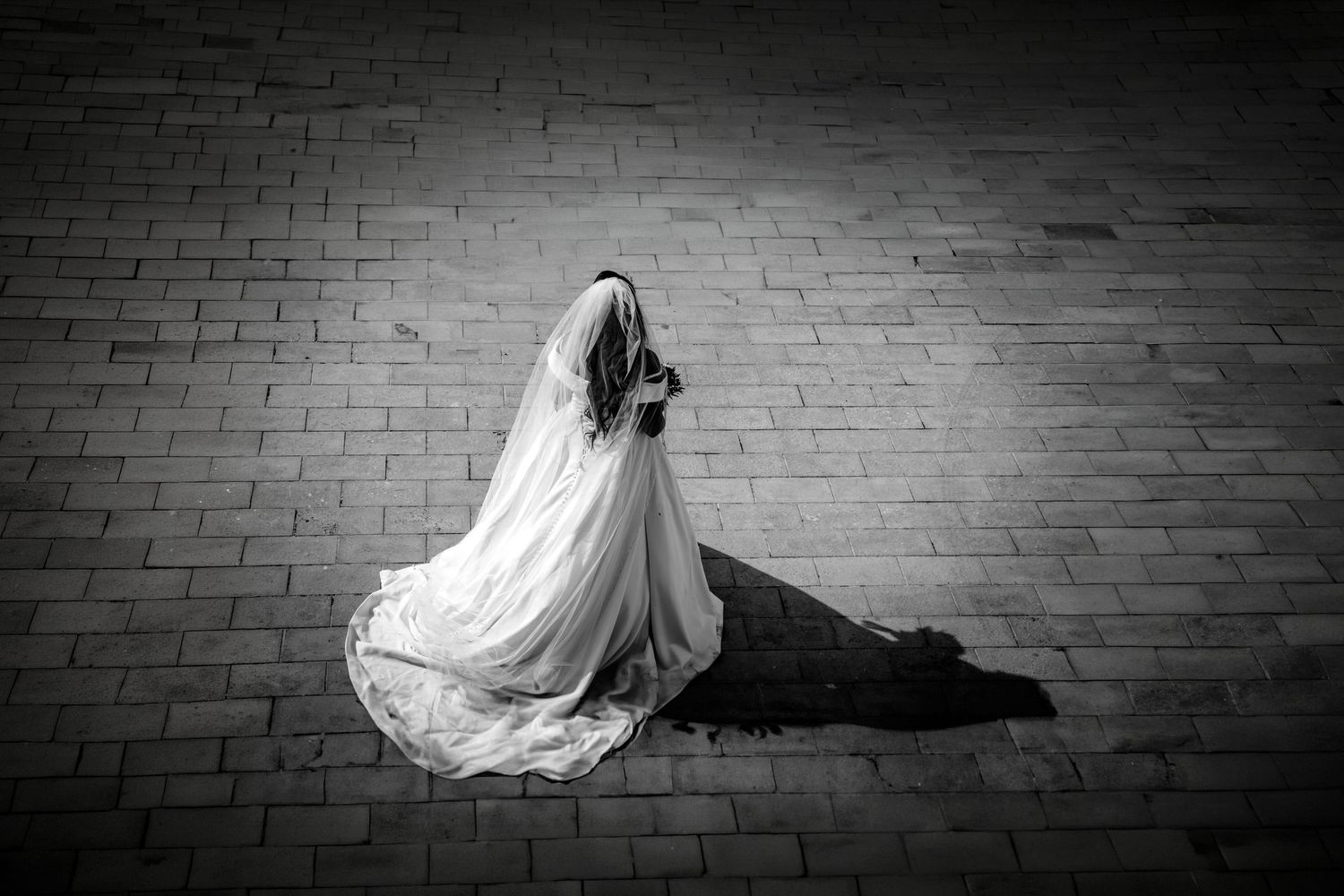 A series of black and white photos showing a flowing white wedding dress against a dark brick wall background.