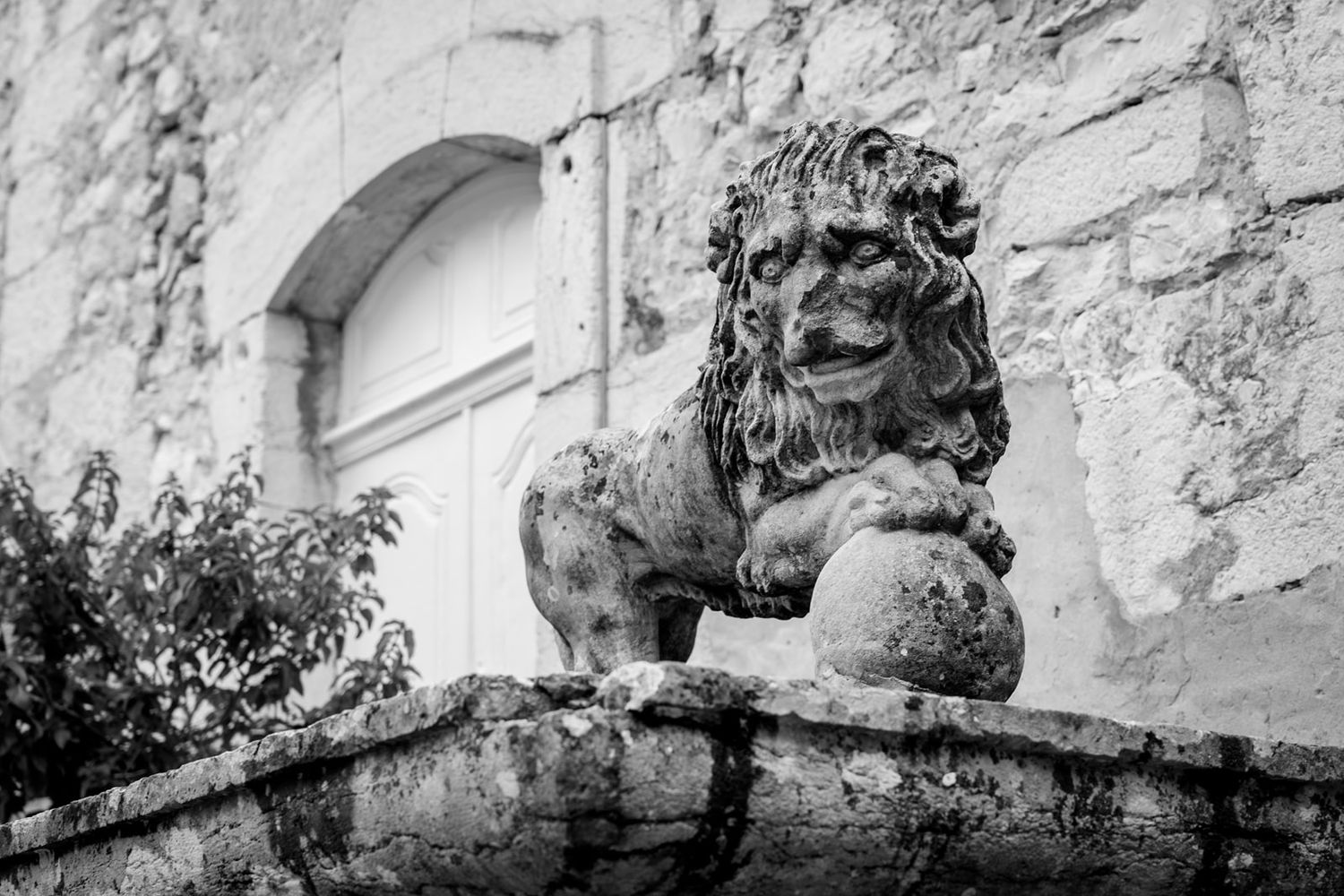 A series of decorative stone lion heads mounted along a white stone wall create a classical architectural detail.