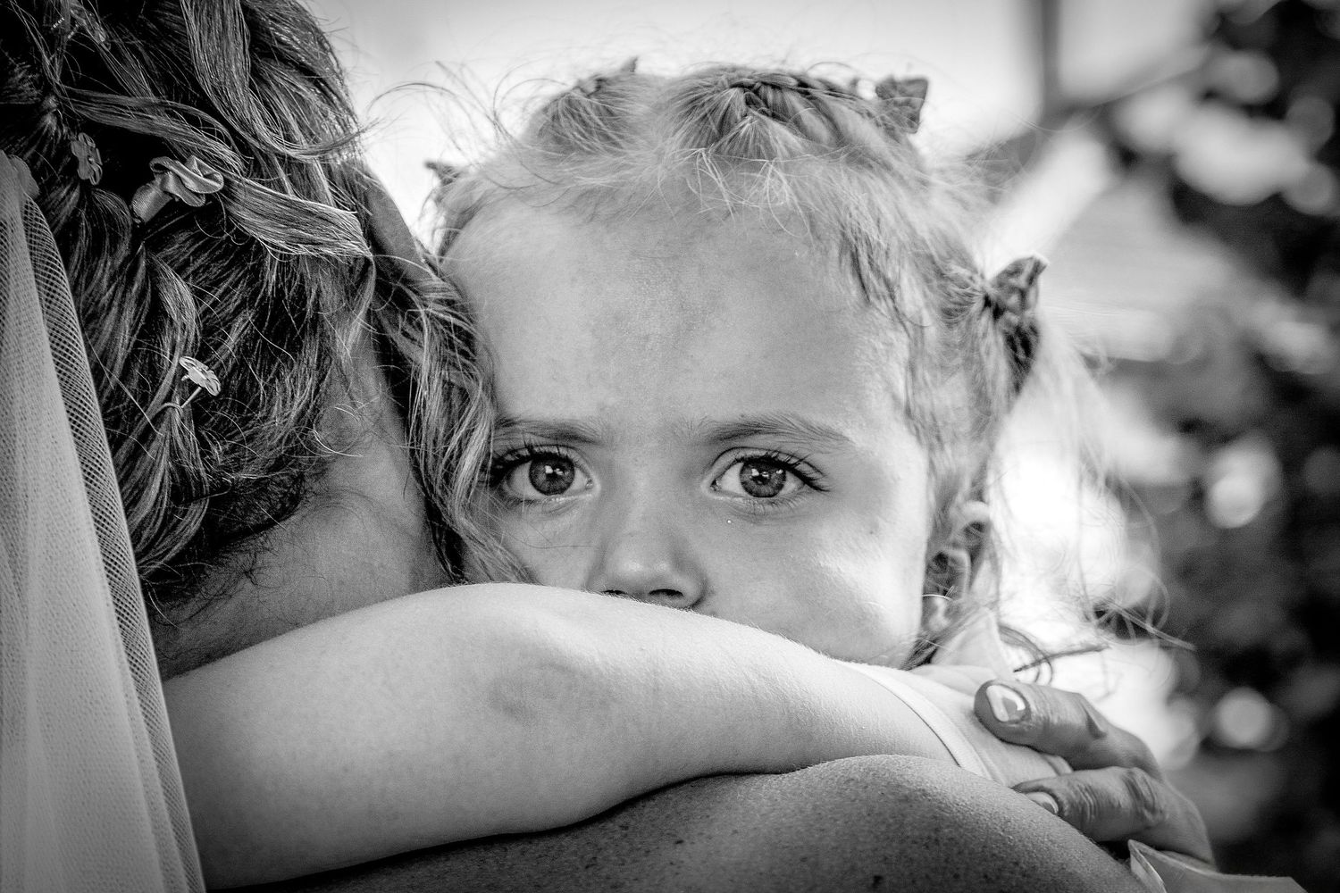 Black and white close up of a small child resting their head on someone's shoulder in an emotional embrace.