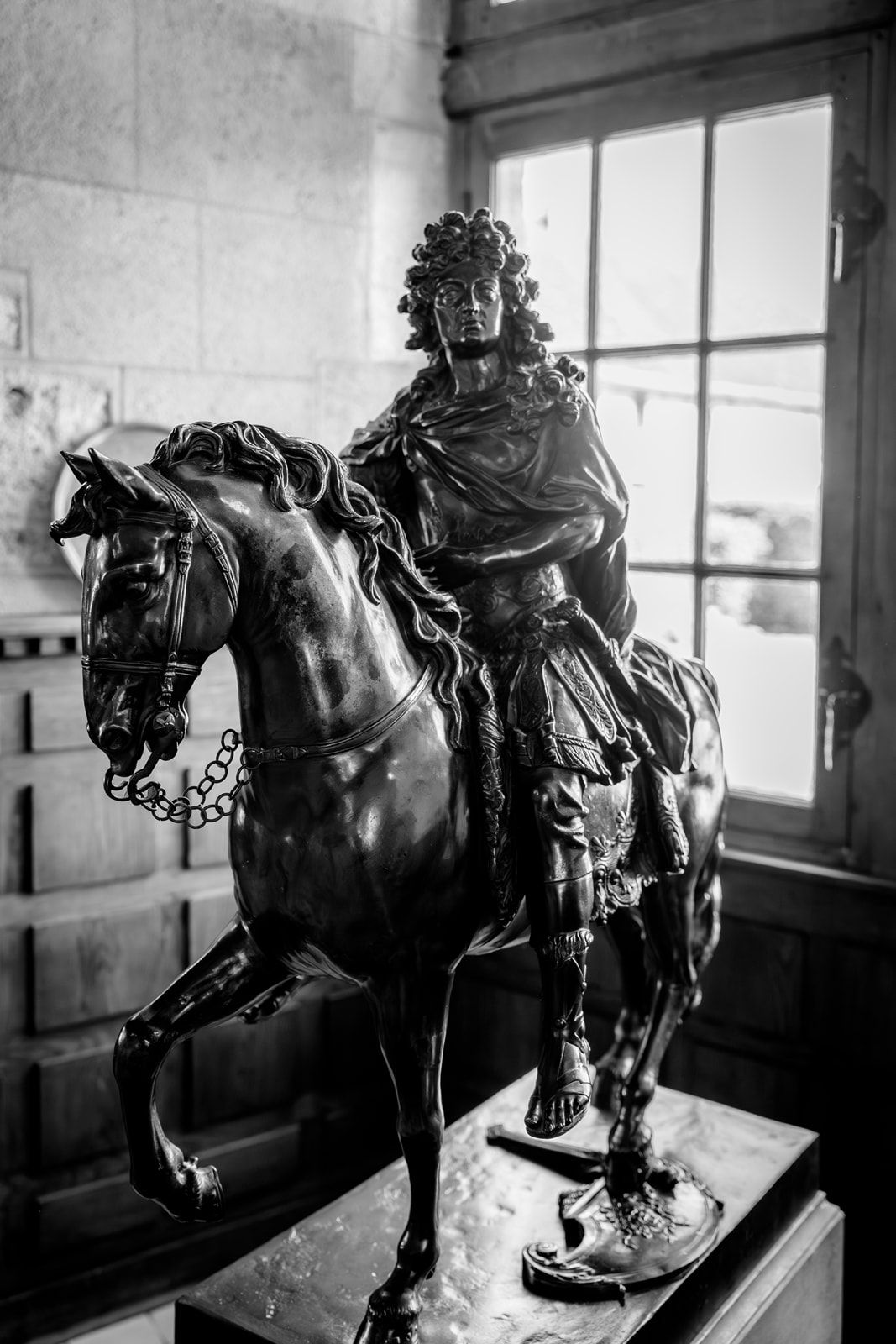 Black and white bronze equestrian statue of a nobleman on horseback displayed indoors.