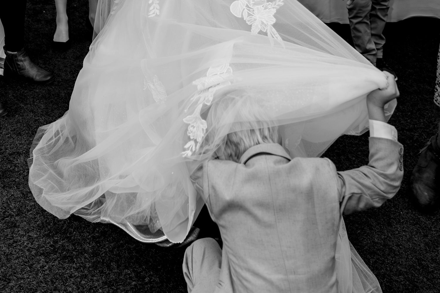 A wedding dress train billows in the wind creating an ethereal silhouette against a dark background.