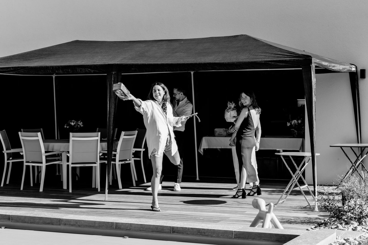 A black and white photograph shows a poolside scene with lounge chairs and people relaxing at a resort.