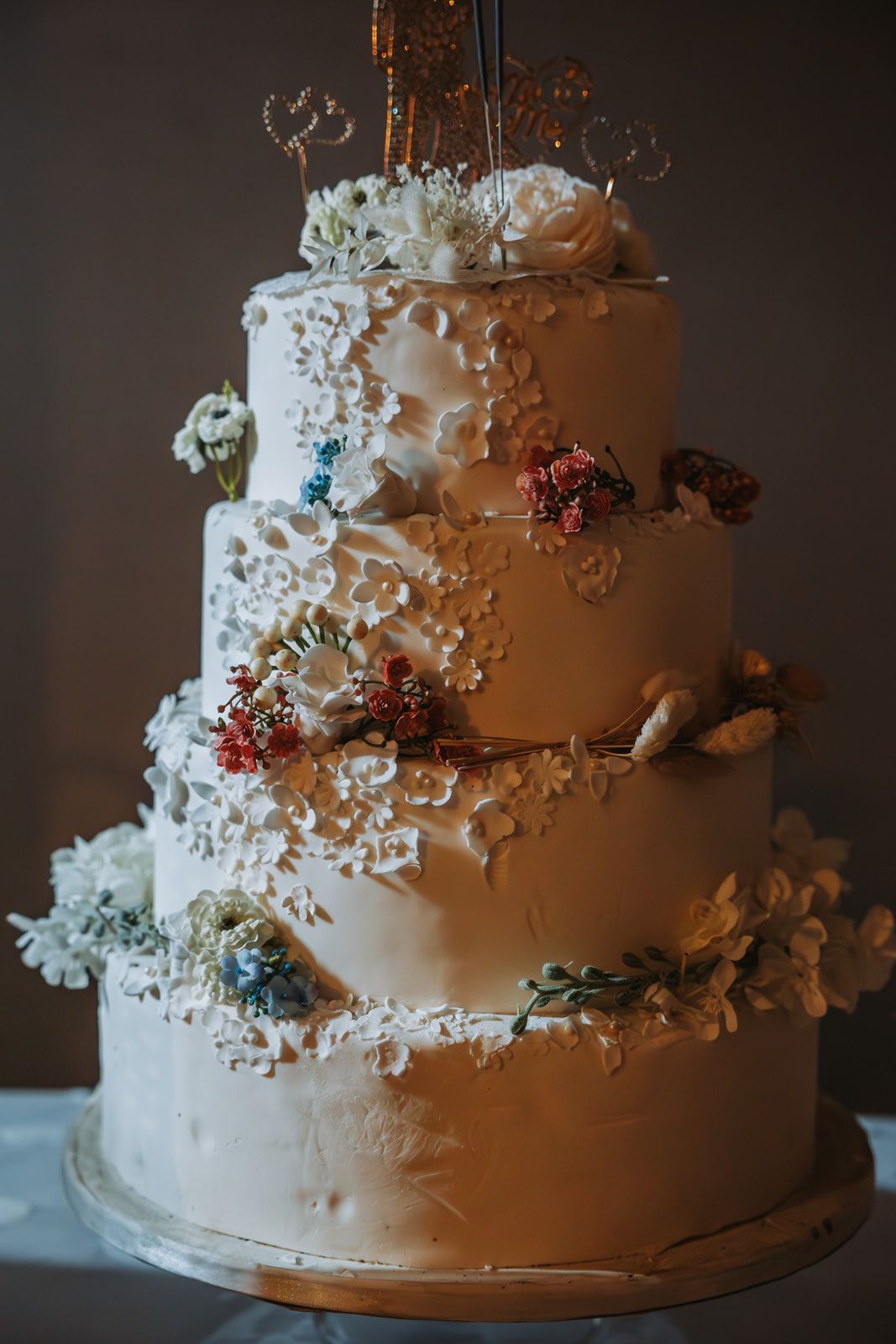 Elegant white wedding cake decorated with delicate lace-like patterns and burgundy floral accents in multiple angles.