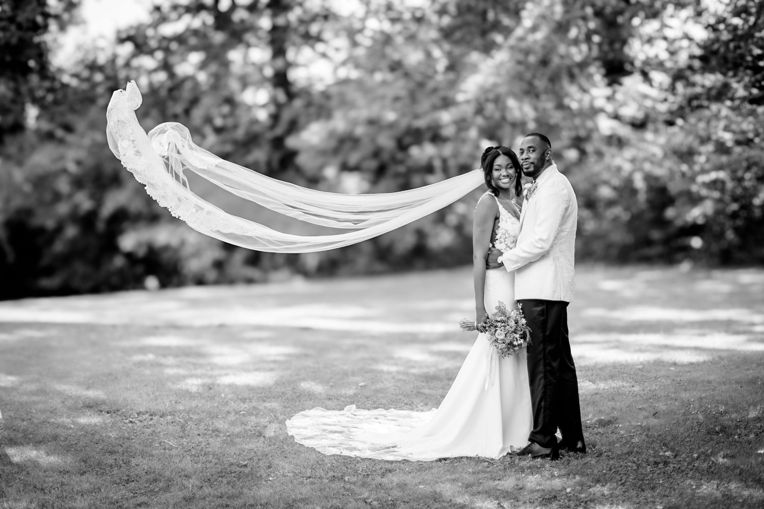 Black and white wedding photos with flowing veil in natural outdoor setting.