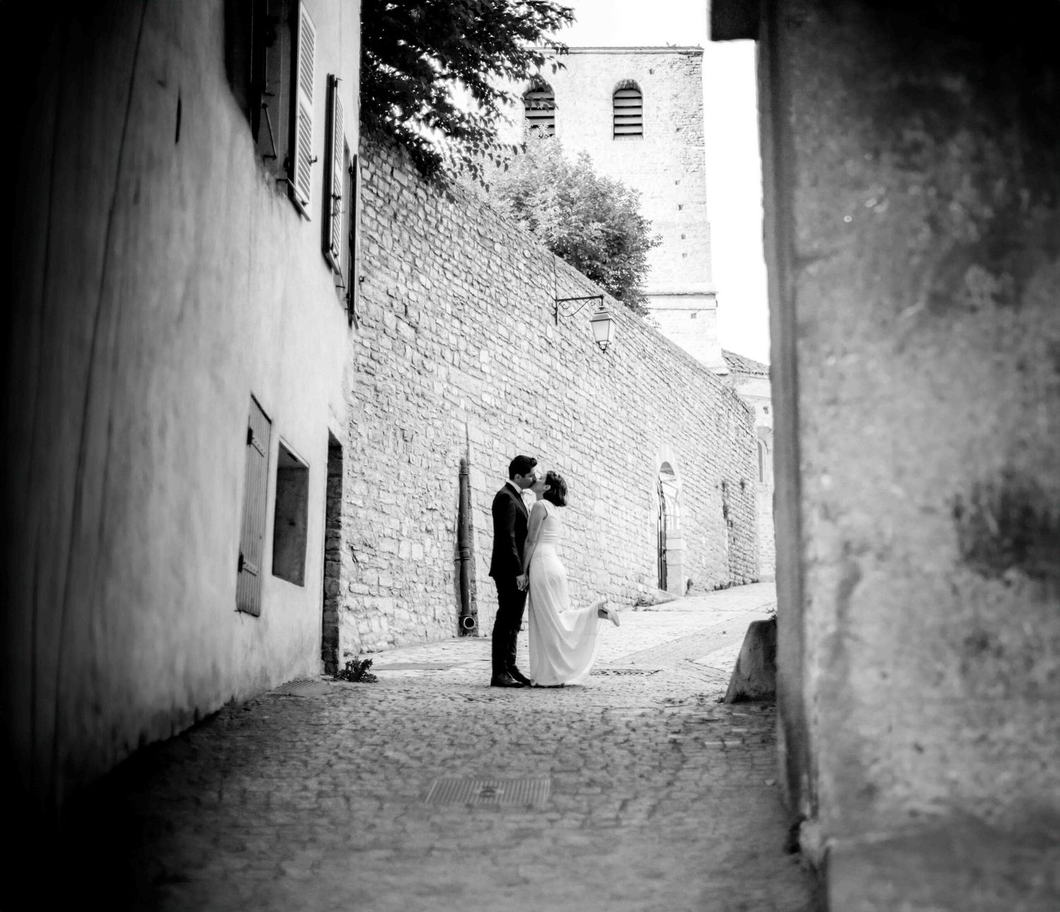 Dramatic black and white wedding photos in a narrow alleyway with stone walls.