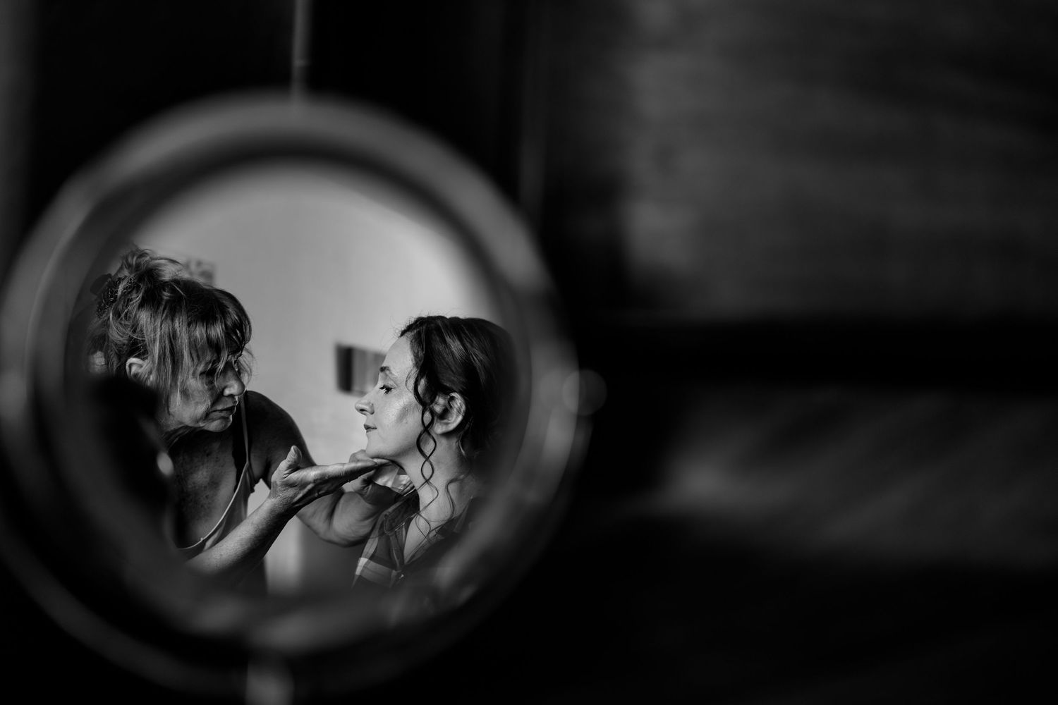 Artistic black and white reflection through mirror shows wedding preparation.