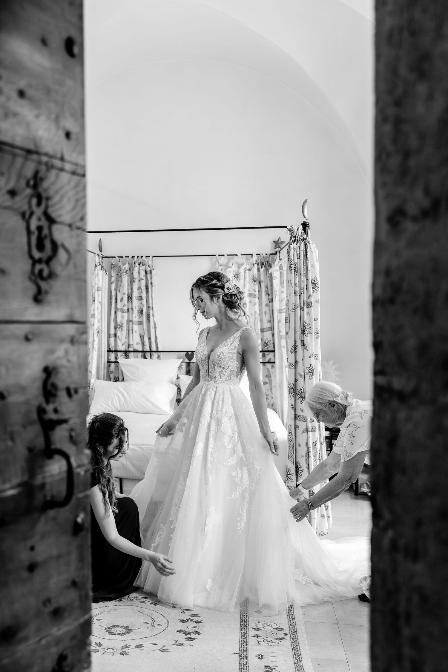 Black and white photos of wedding dresses displayed on hangers against a rustic wall.
