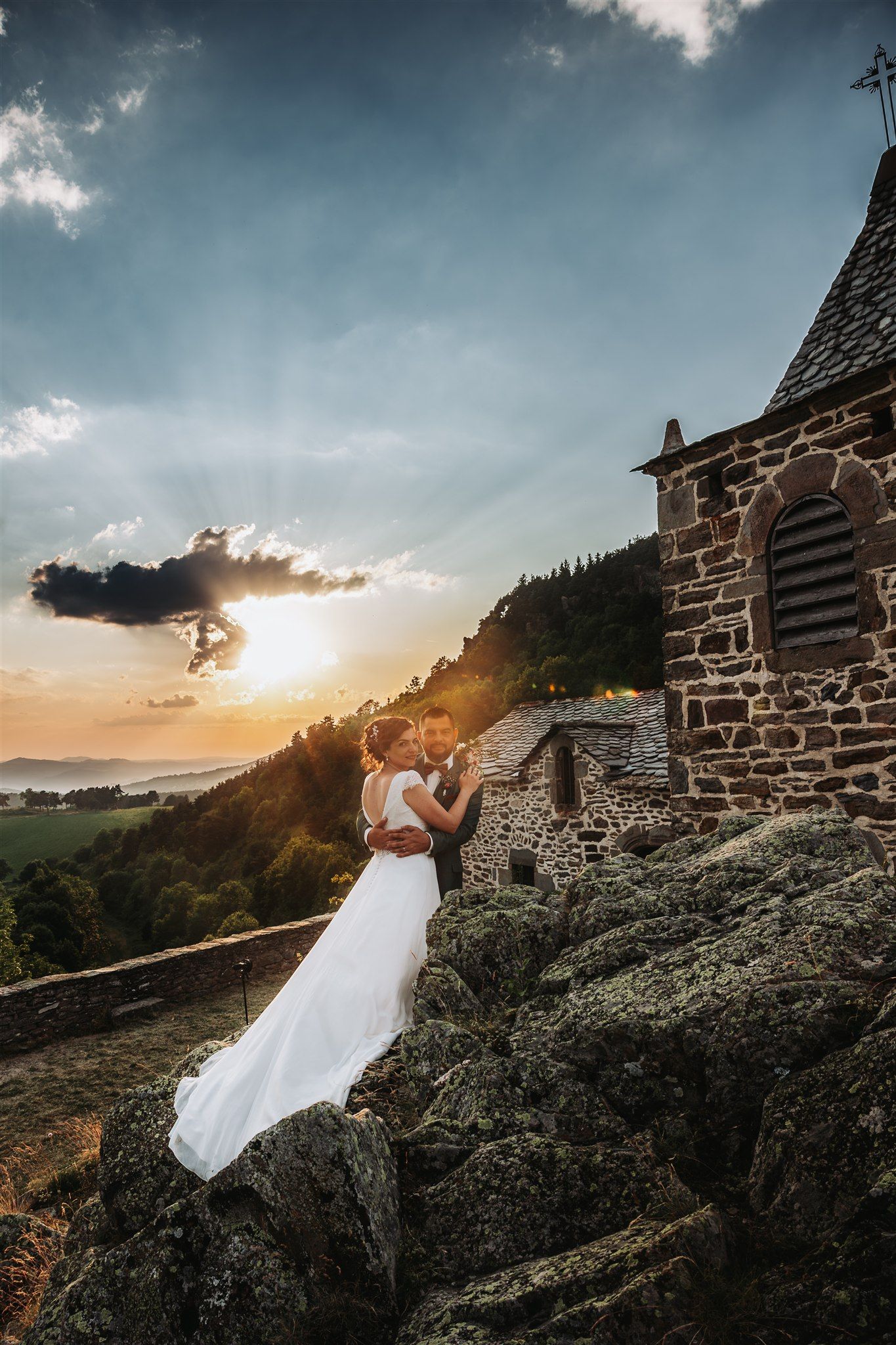 Dramatic sunset wedding photos against stone castle walls and mountain backdrop.