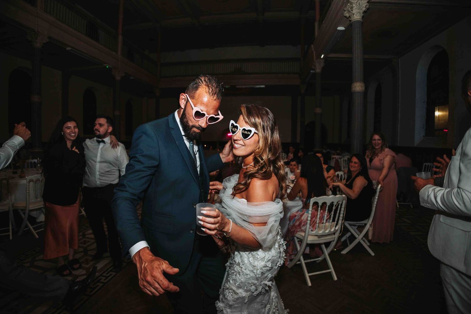 Guests dancing and celebrating at an evening wedding reception in a grand ballroom.