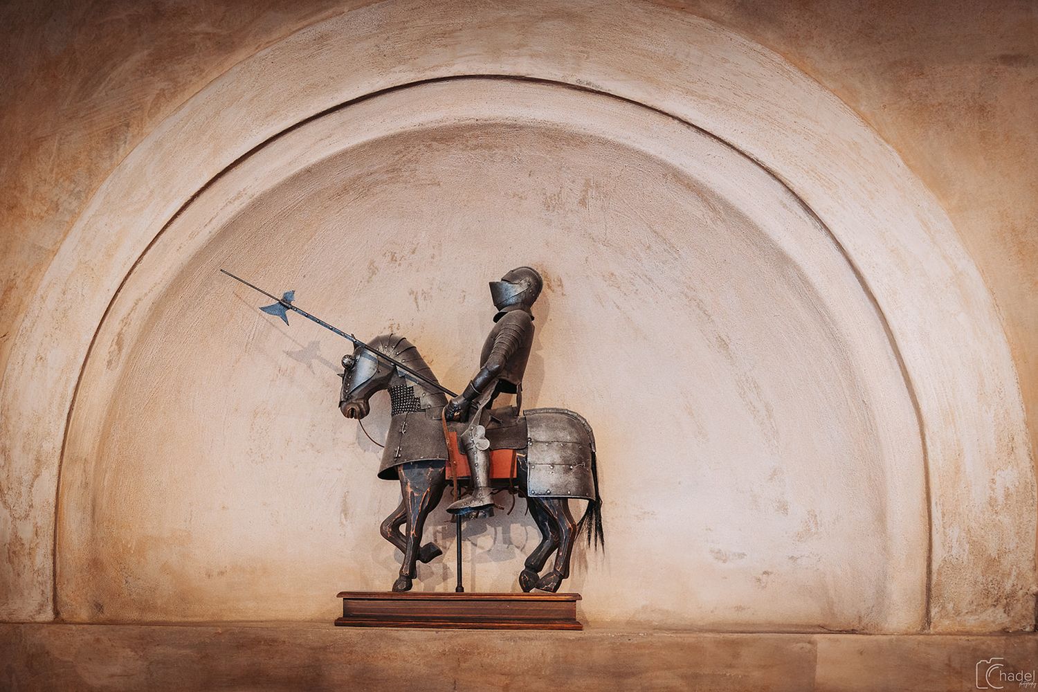A series of vintage equestrian statues and sculptures displayed in arched alcoves against a textured beige wall.
