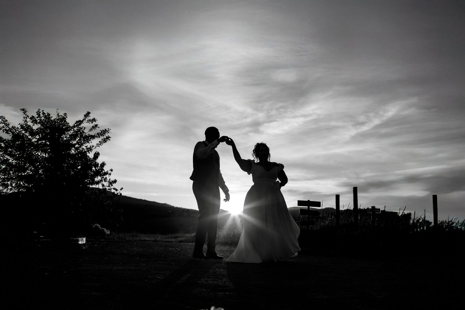 Silhouette of a dancing couple against a dramatic sunset sky.