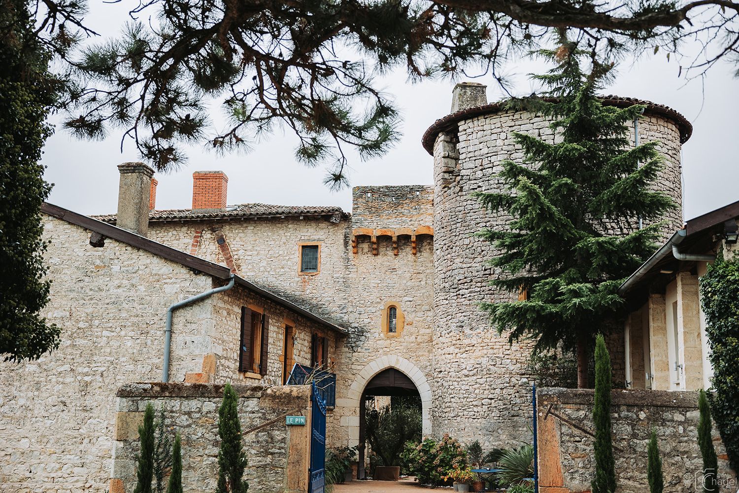 Ancient stone castle walls and towers stand against a cloudy sky in a picturesque medieval village.