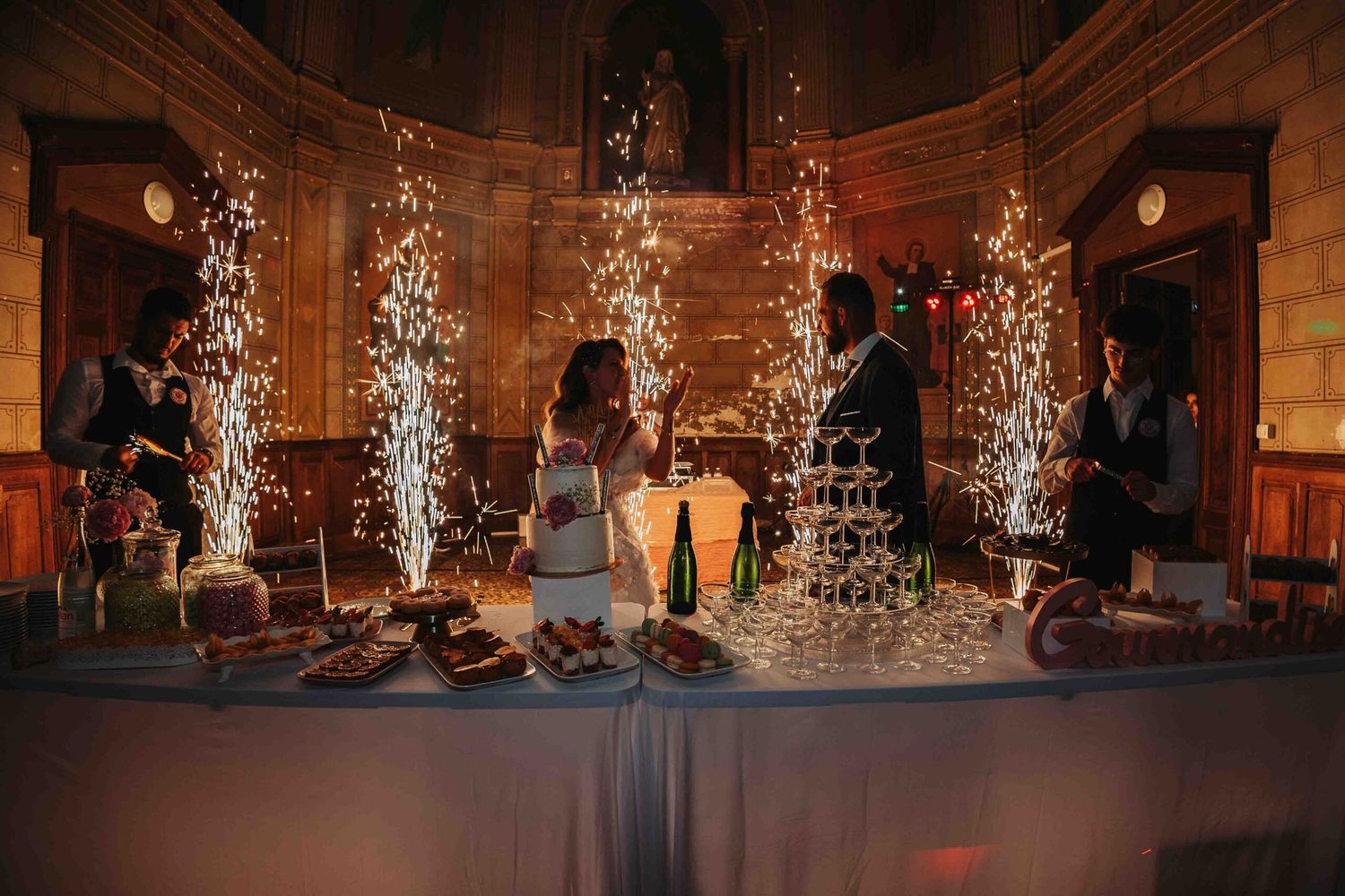 Musicians perform on stage with dramatic pyrotechnic sparkler effects creating a magical atmosphere at an indoor venue.
