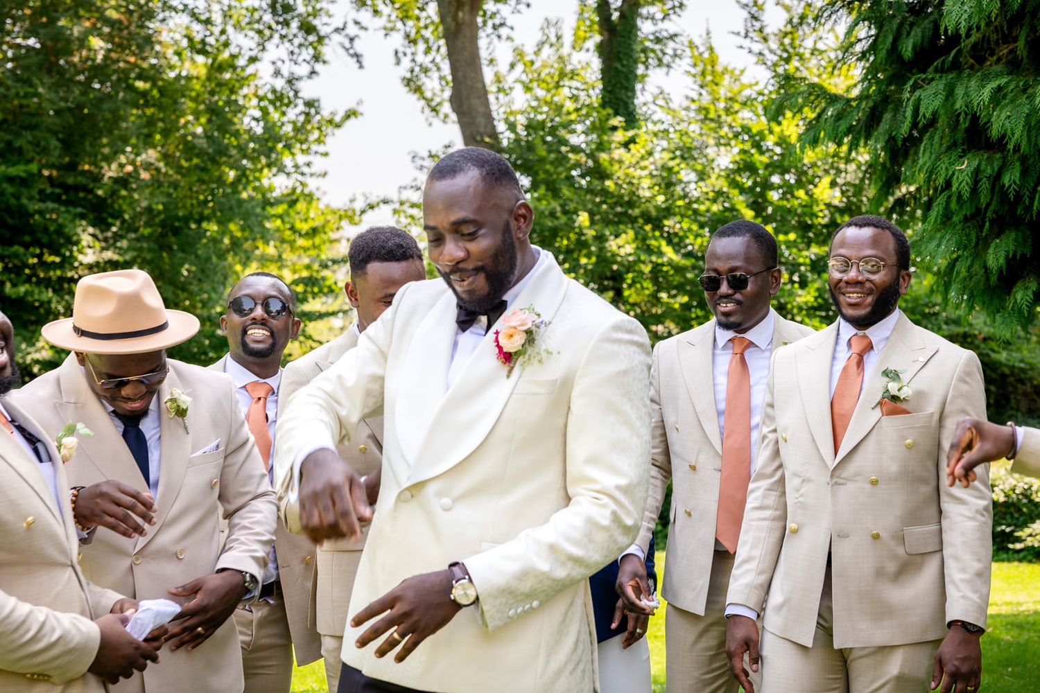 A sequence of candid moments at an outdoor wedding celebration showing joyful interactions between guests in cream suits.