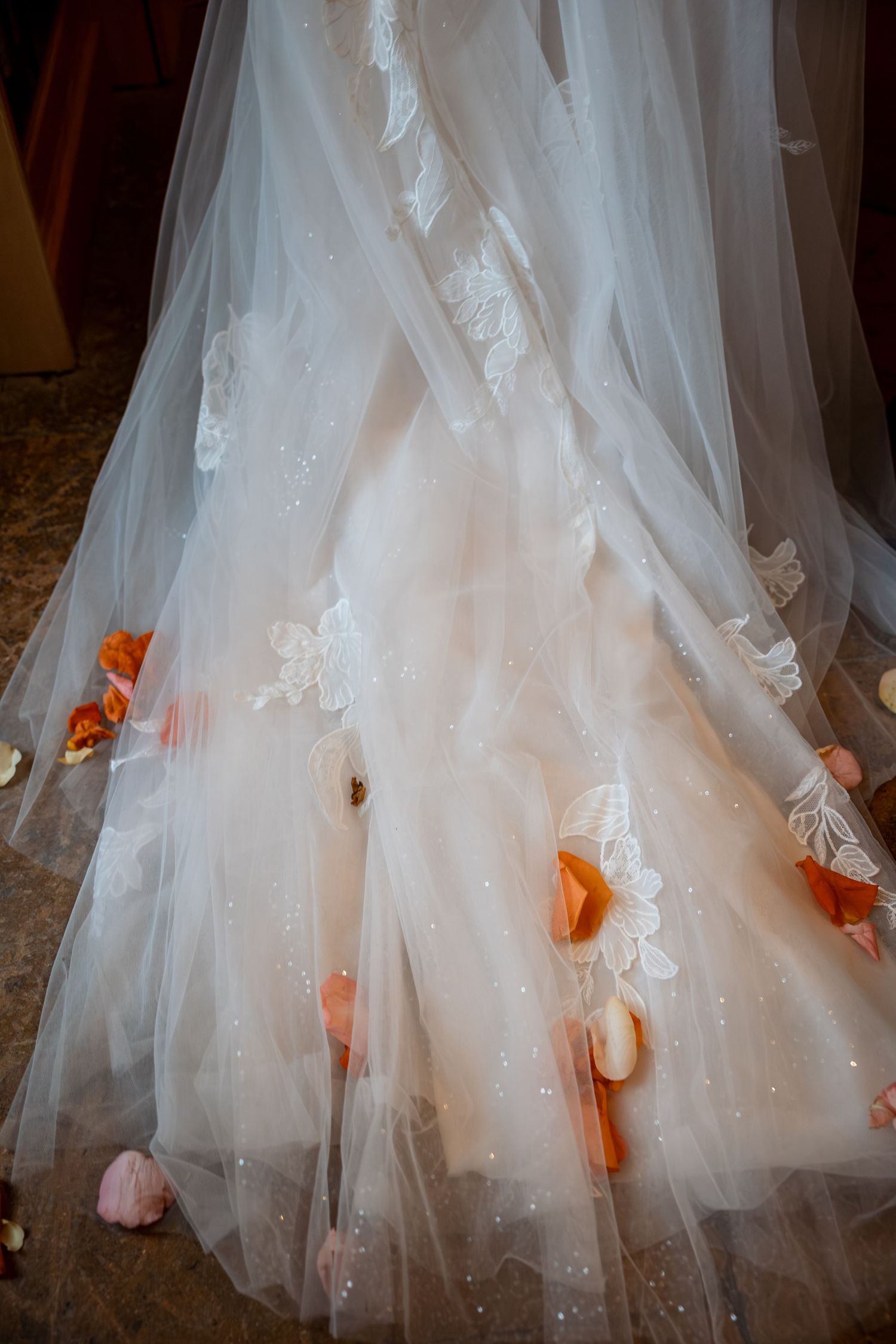 Close-up details of intricate white wedding dress with delicate lace and tulle layers.
