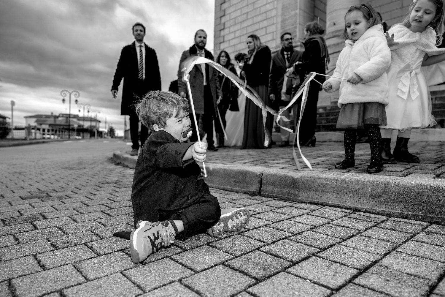 Black and white panoramic sequence showing people sitting and interacting on cobblestone streets.