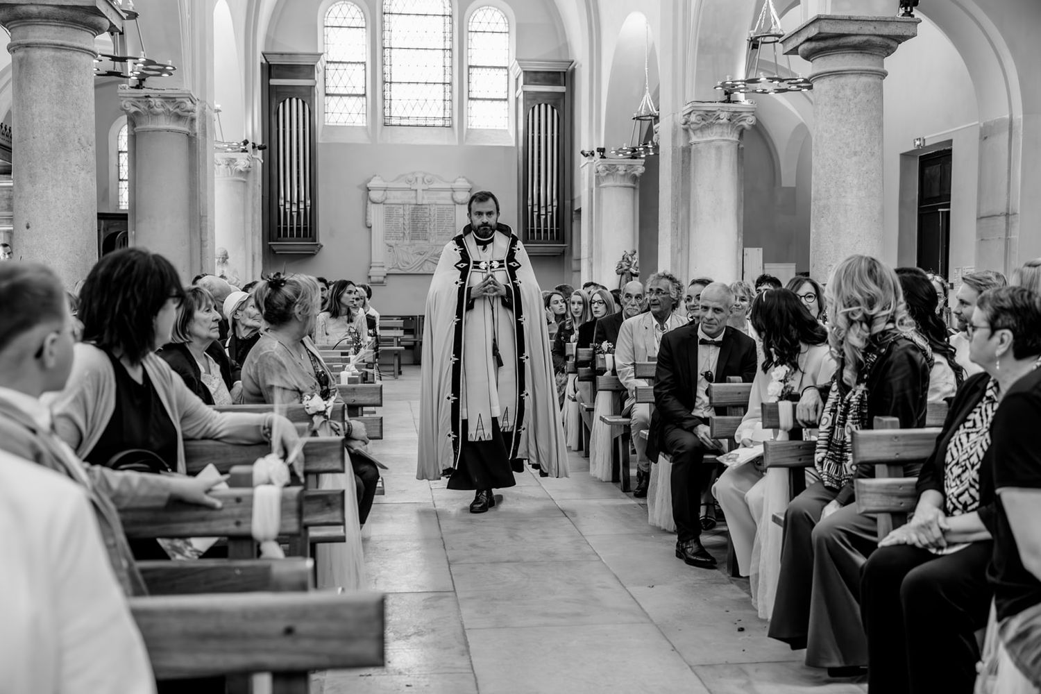 A wedding ceremony takes place in a grand church with white columns and arched windows.