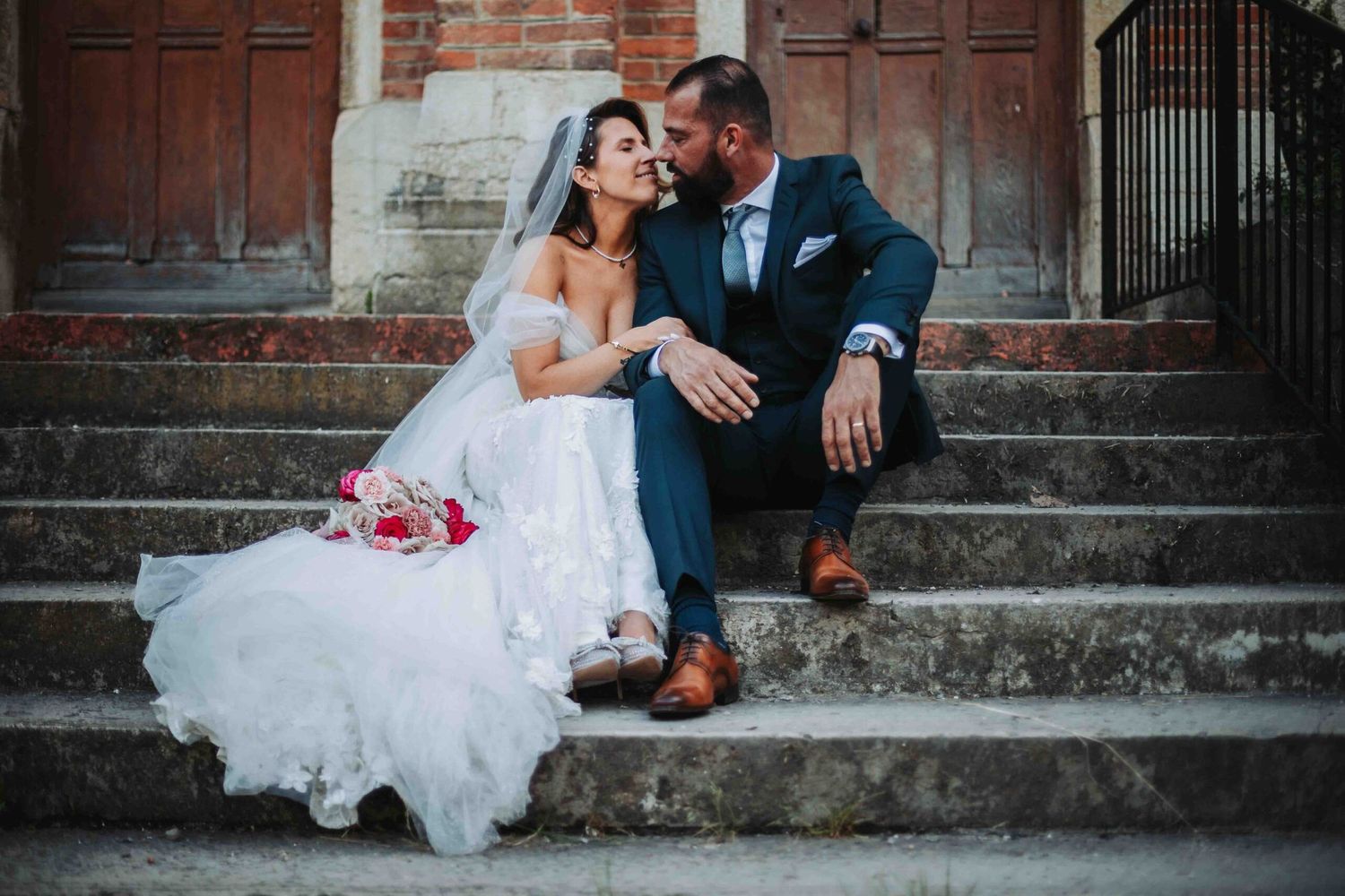 Romantic wedding portraits taken against historic brick church architecture.