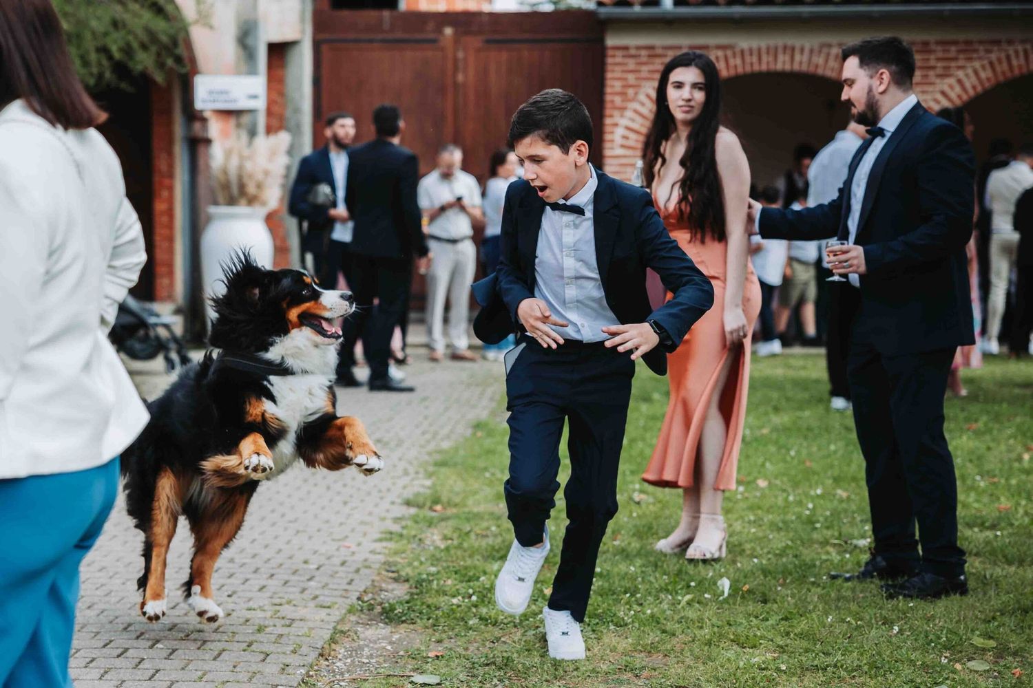Wedding guests mingling and socializing on an outdoor cobblestone patio.