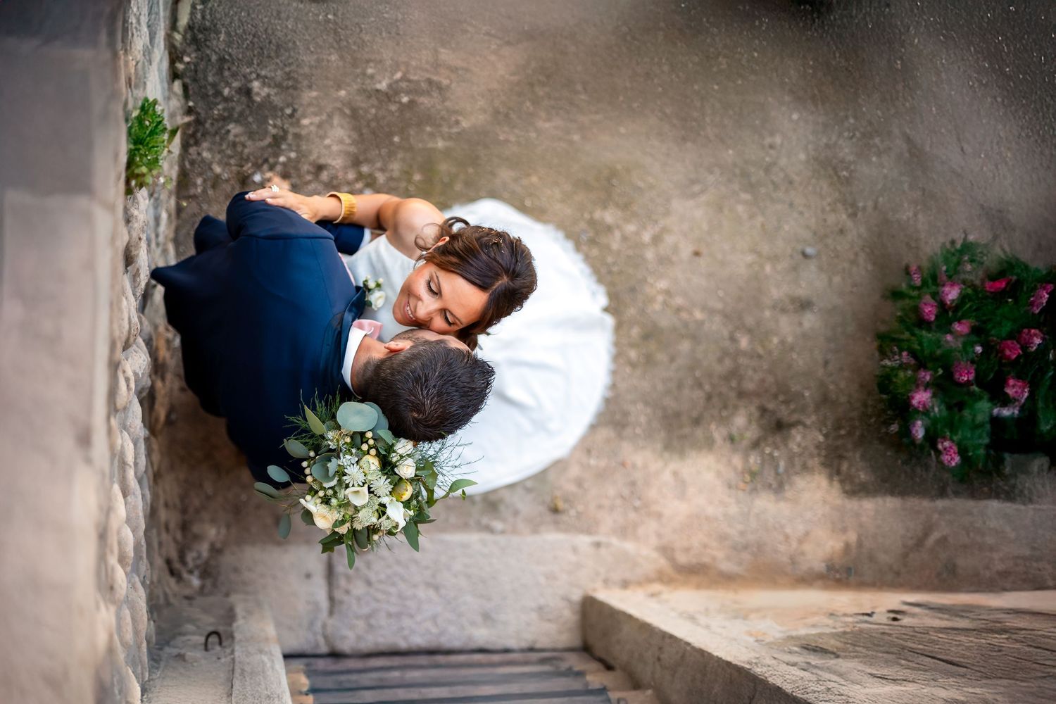 Wedding couple poses for creative ground-level shots on textured concrete surface.