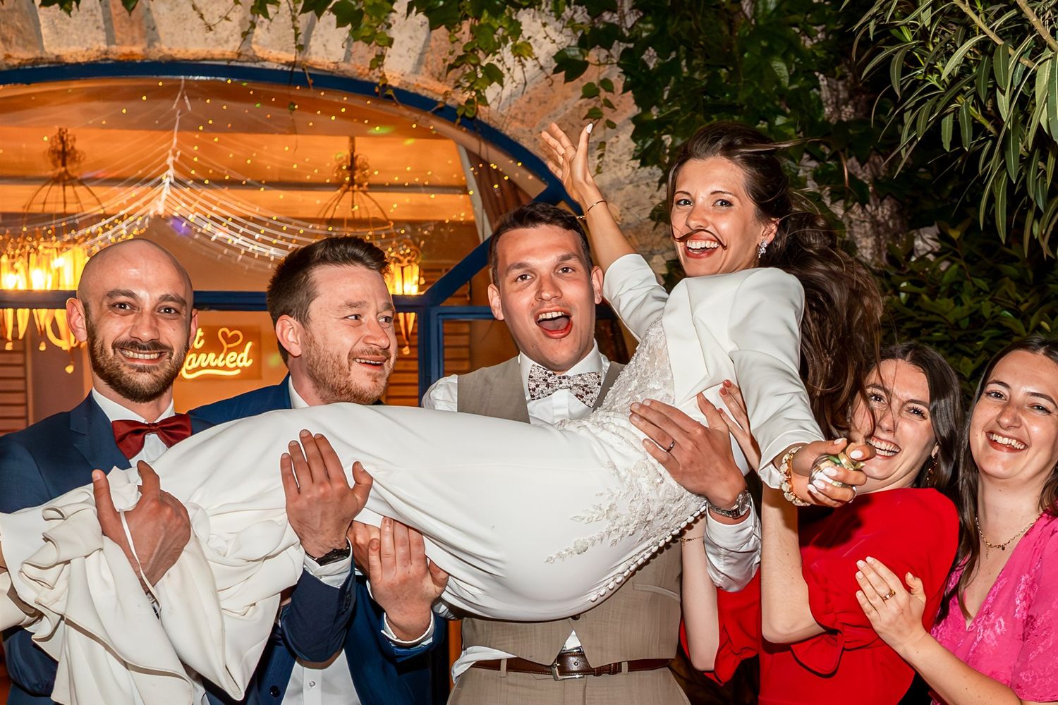 A lively group of wedding guests dancing and celebrating together on a dance floor at an indoor reception.
