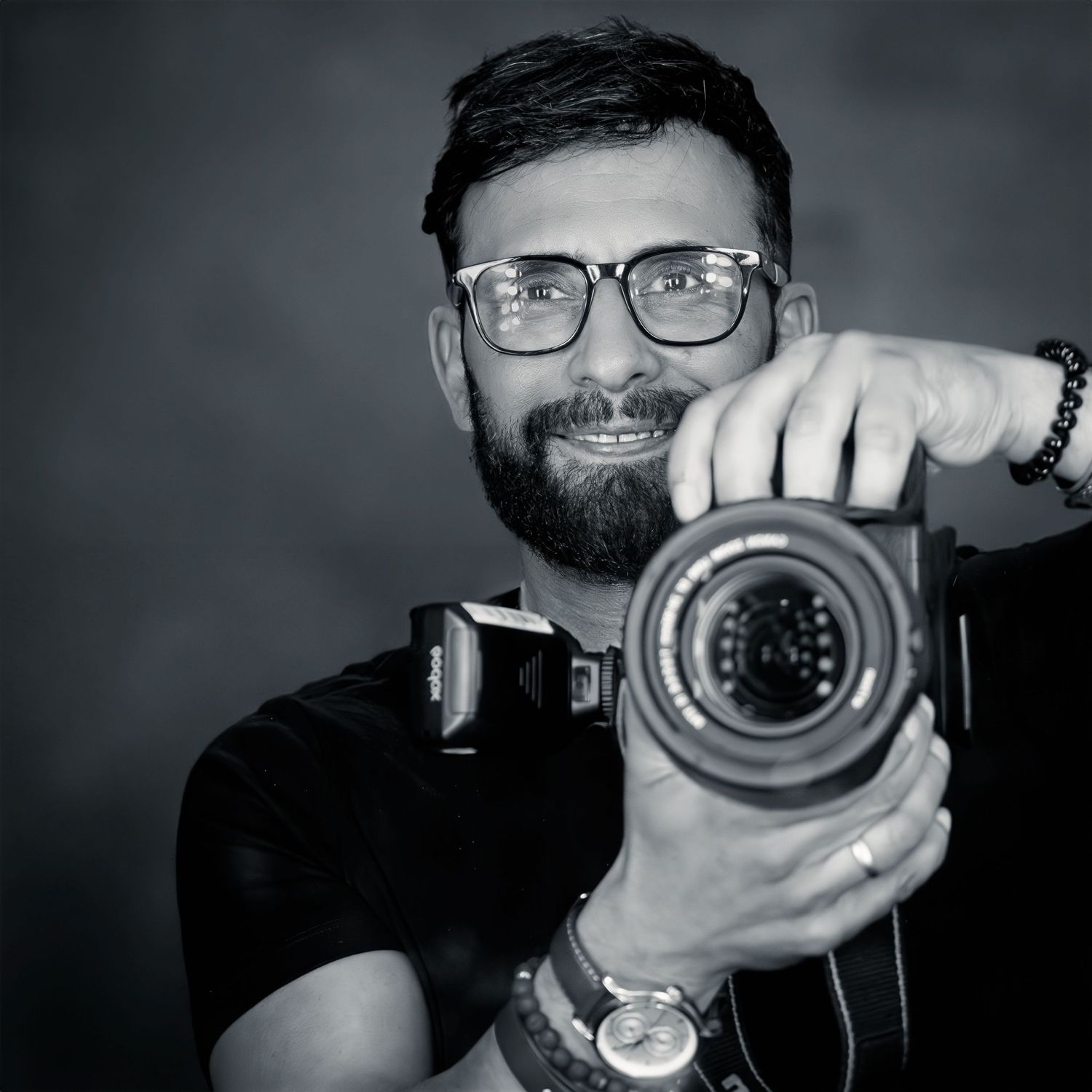Professional photographer holding camera in black and white portrait style.