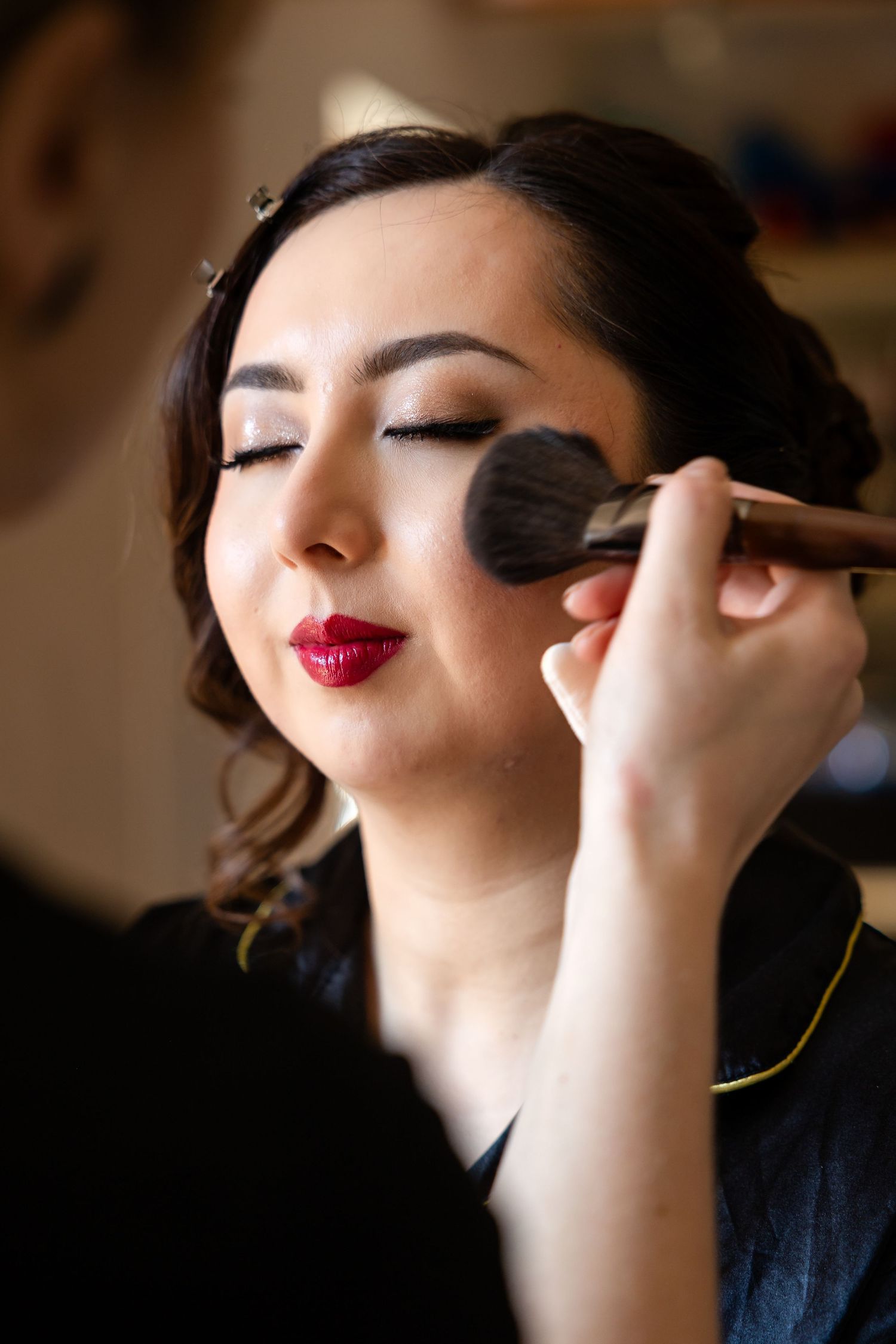 Professional makeup artist applying eyeshadow during bridal preparation.