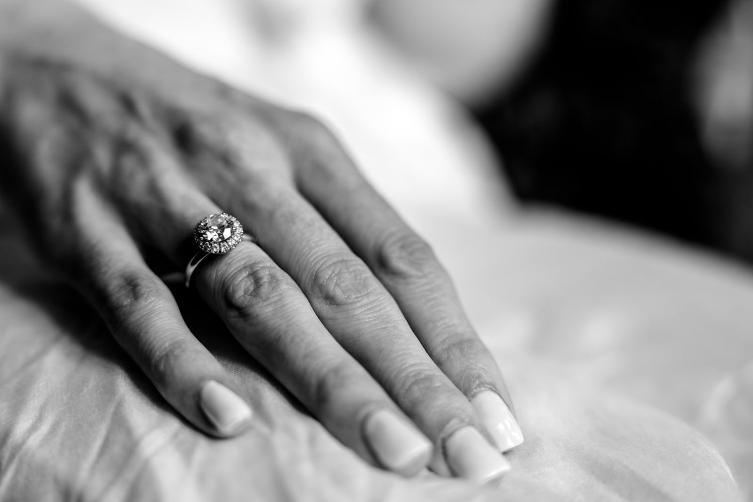 Close-up black and white photo of hands exchanging wedding rings during a marriage ceremony.
