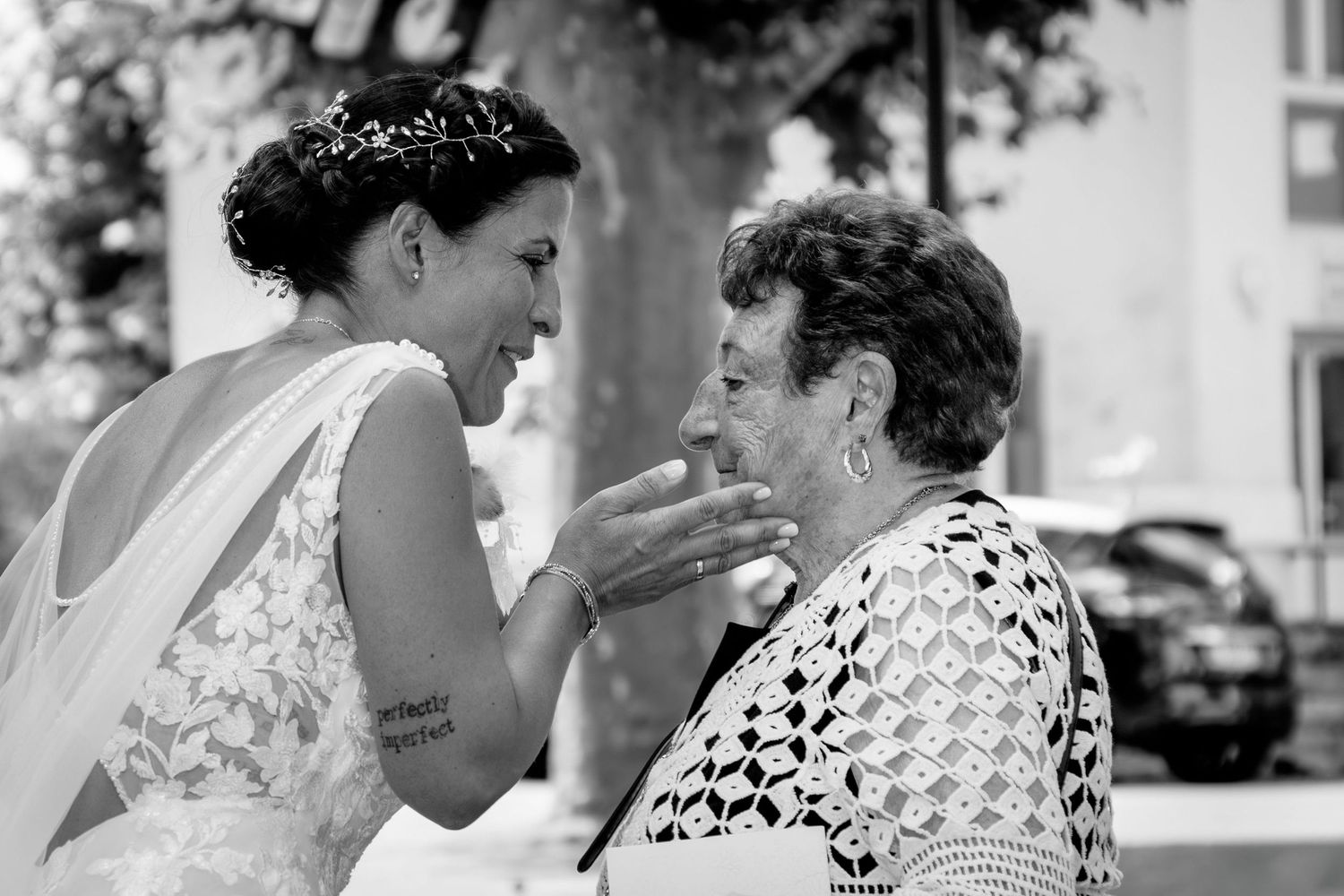 A touching black and white moment between a bride in a lace dress and an elderly woman sharing an emotional exchange.