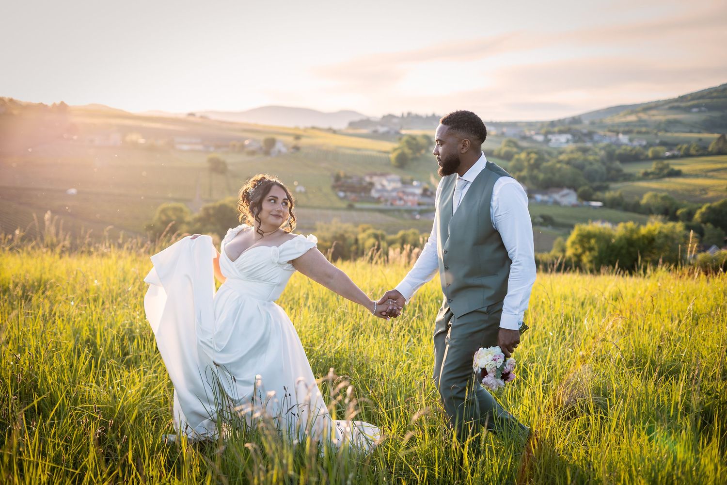 couple de mariés se tiennent la main au couché de soleil