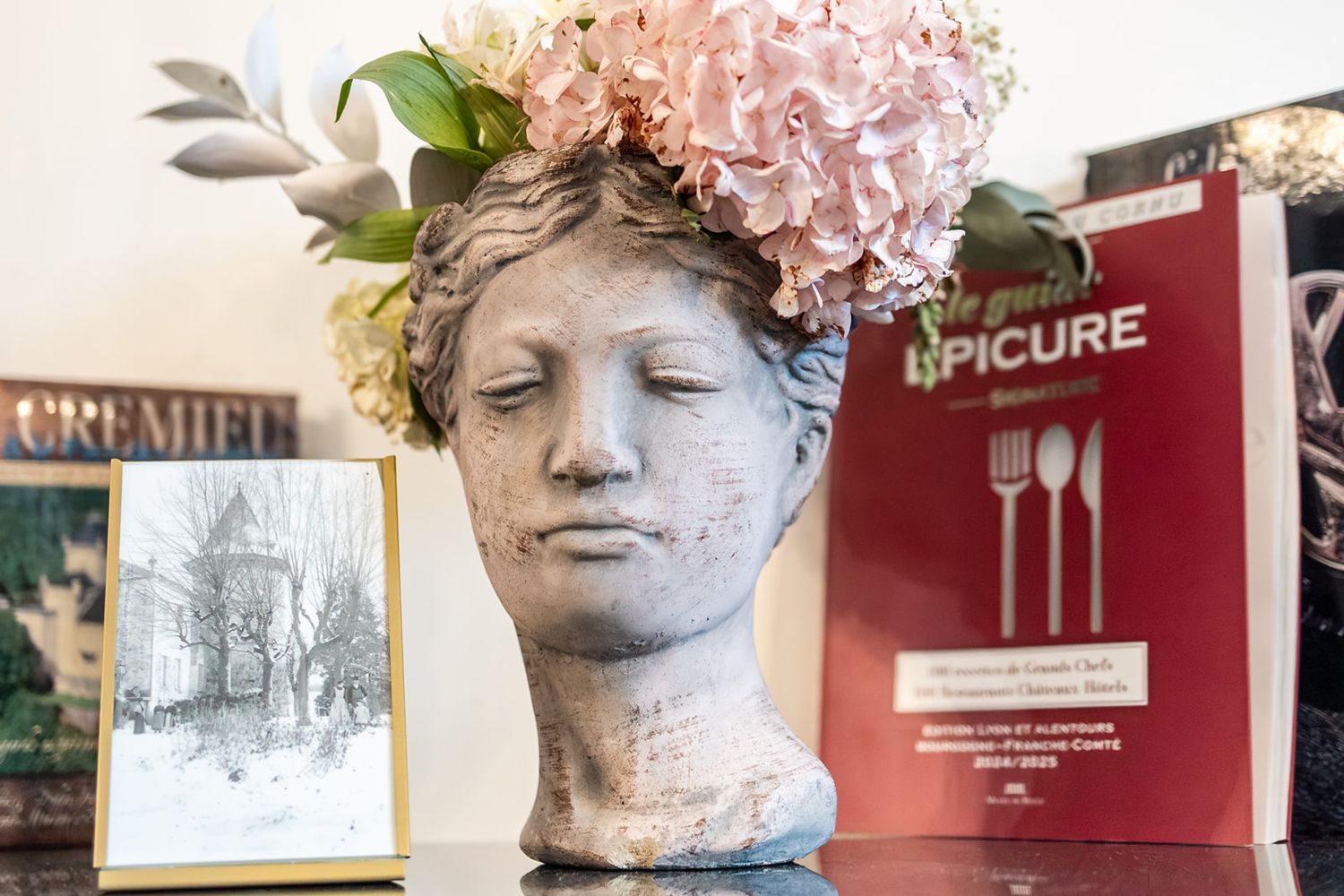 A collection of classical busts and sculptures displayed in a museum gallery with pink floral decorations.