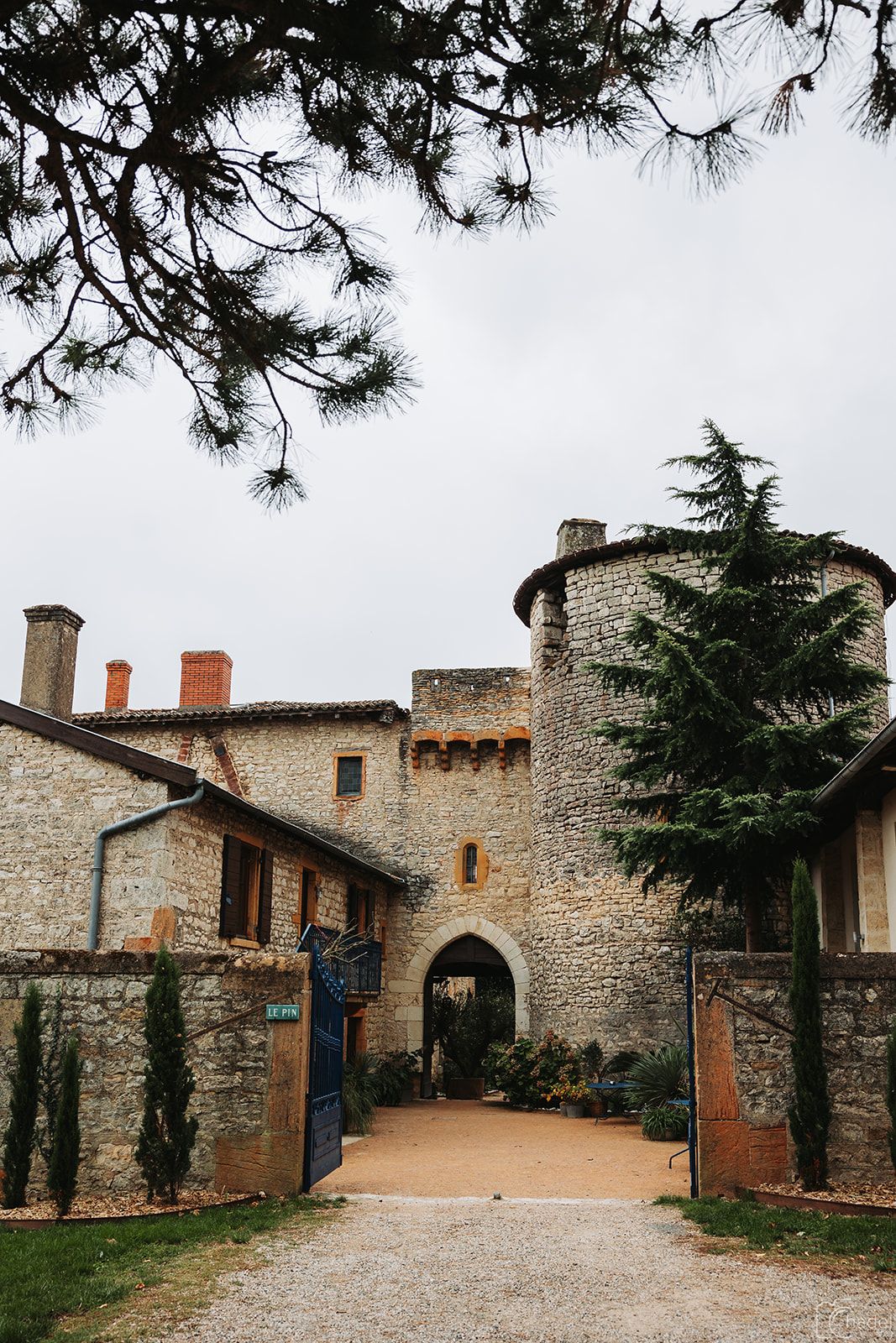 Stone walls and archways line a rustic courtyard path in a medieval European village setting.