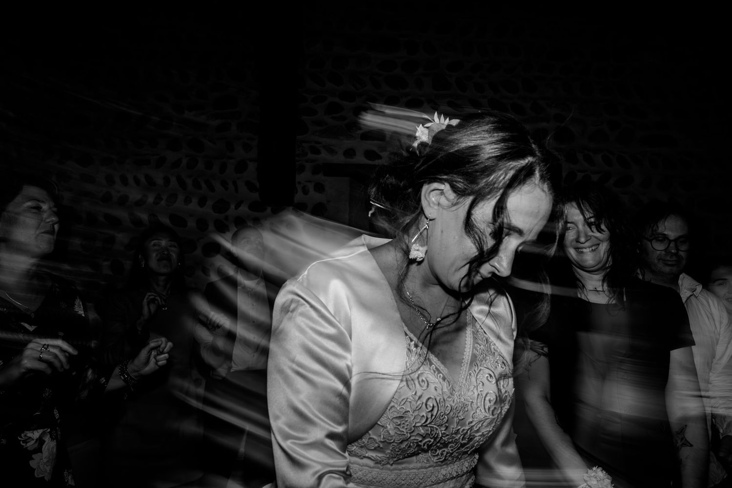 A black and white photograph of someone dancing at a party wearing a white dress and moving with motion blur.